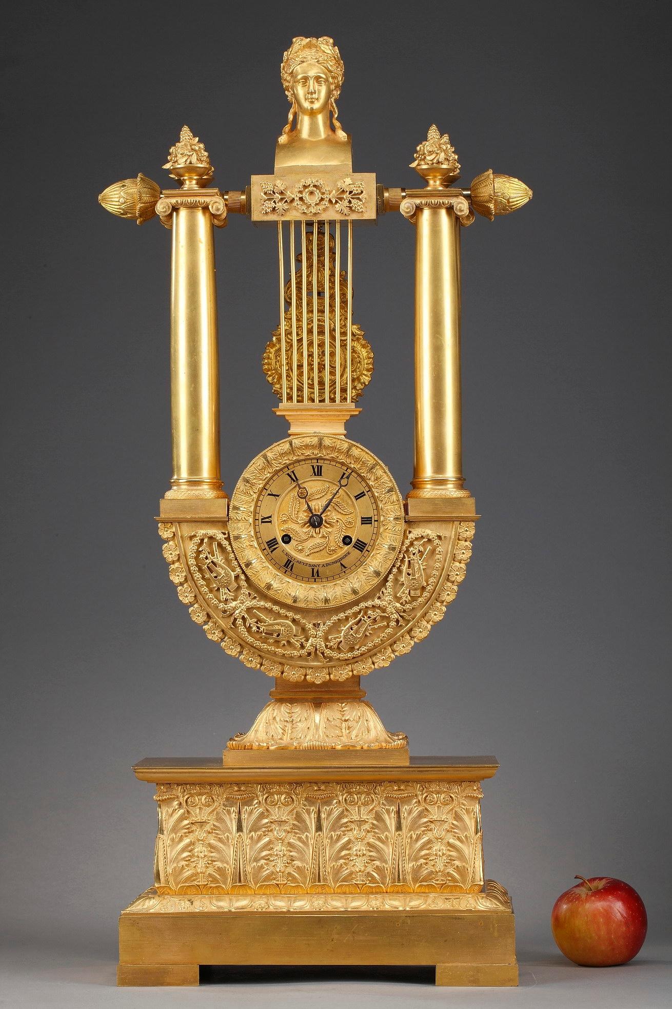Designed in the Empire style, this large mantel clock is mounted in a beautiful lyre-form ormolu frame accentuated by exquisitely detailed decoration composed of acanthus leaves, flowers and music trophies. The gilt bronze dial is signed: 