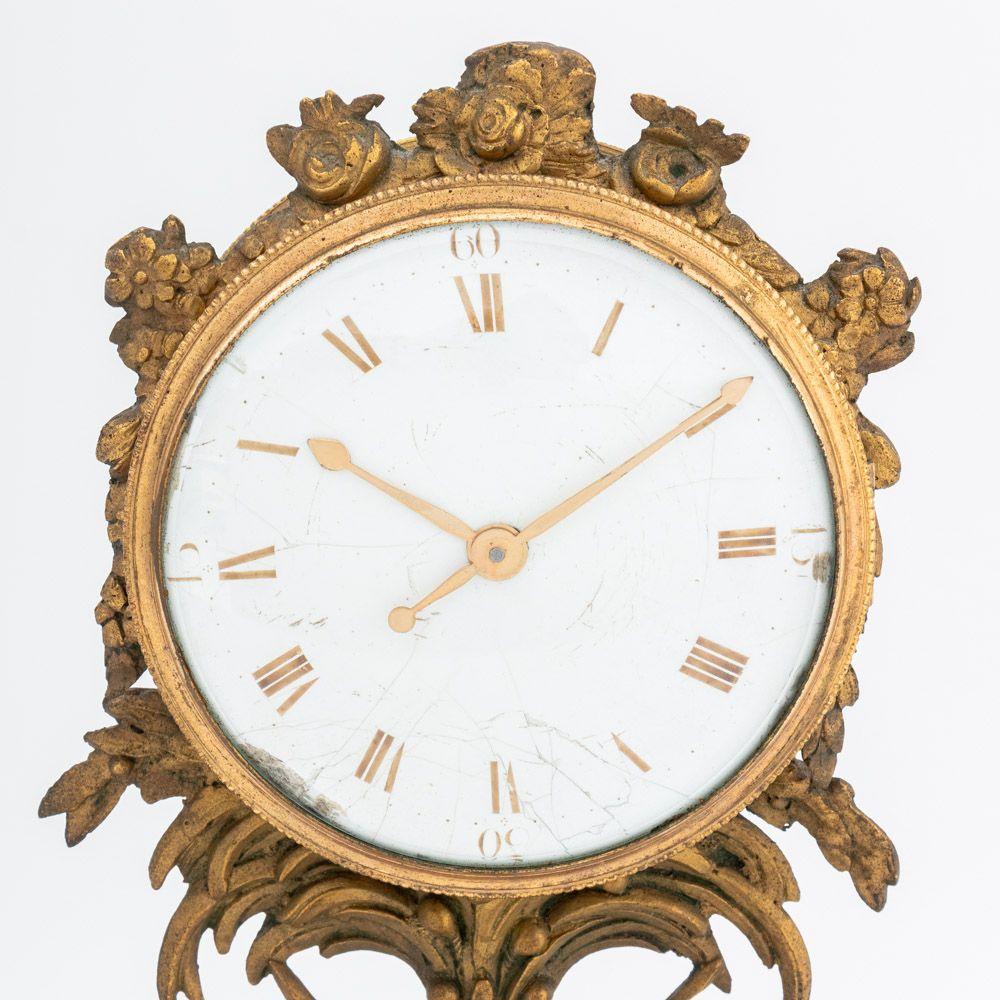 French Empire Style Gilt Metal Ebonized Wood Mantle Clock, 19th century, with porcelain clock face framed by floral motif with flag and hat, flanked by a man and woman waving on ebonized rectangular base with gilt metal mounts. 12.5