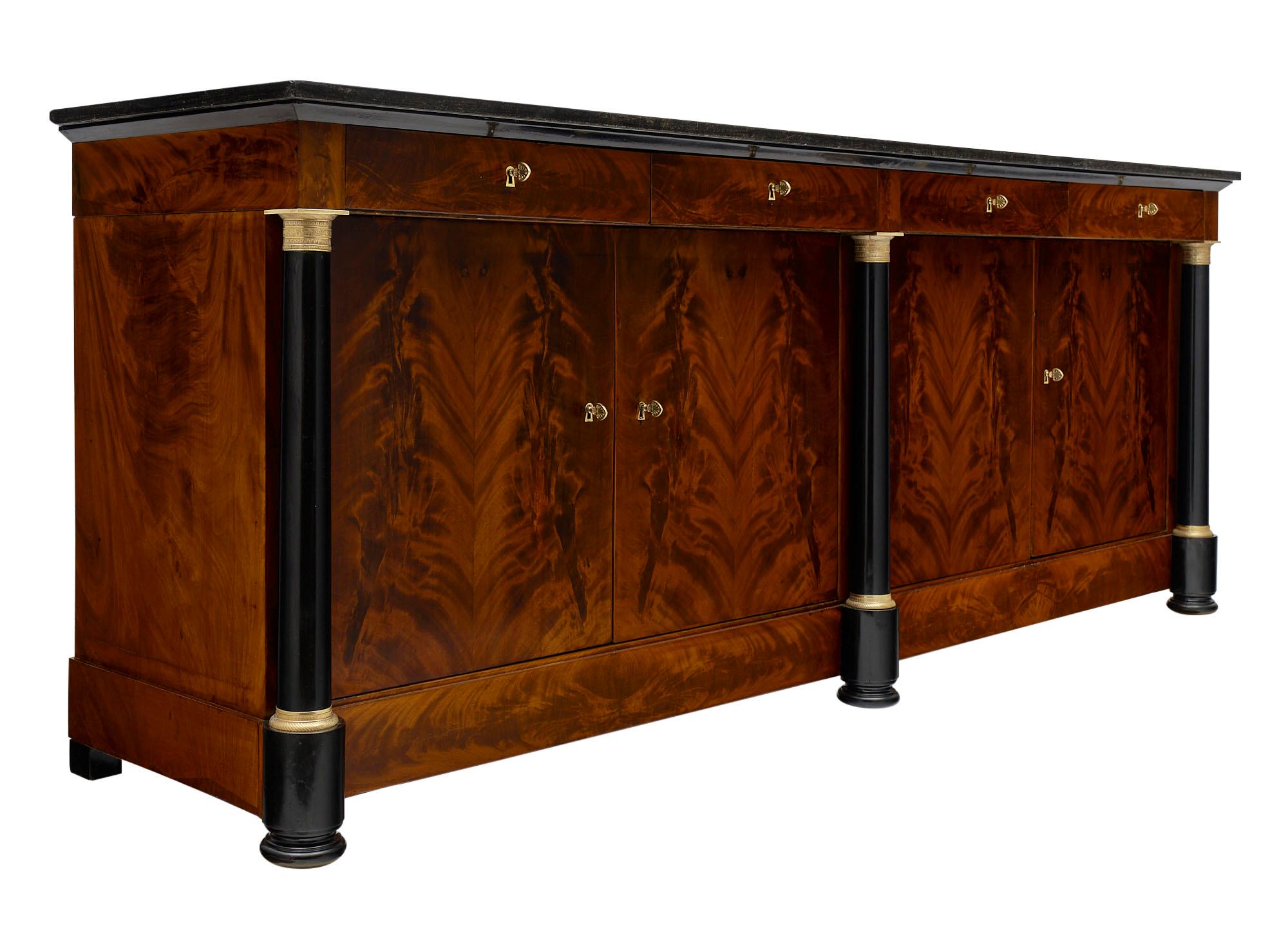 Empire style grand buffet made of Cuban flamed mahogany and featuring ebonized detached columns. We love the gilt bronze hardware which contrast beautifully with the piece! The buffet has been finished in a museum-quality French polish. There are