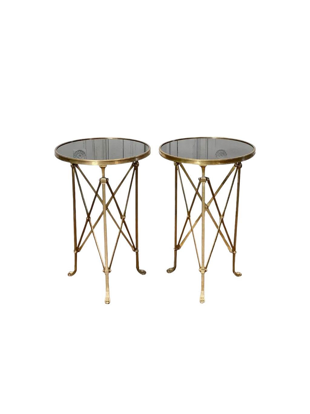 A pair of black granite top empire style Gueridon tables. Brass with paw feet and a circular top.