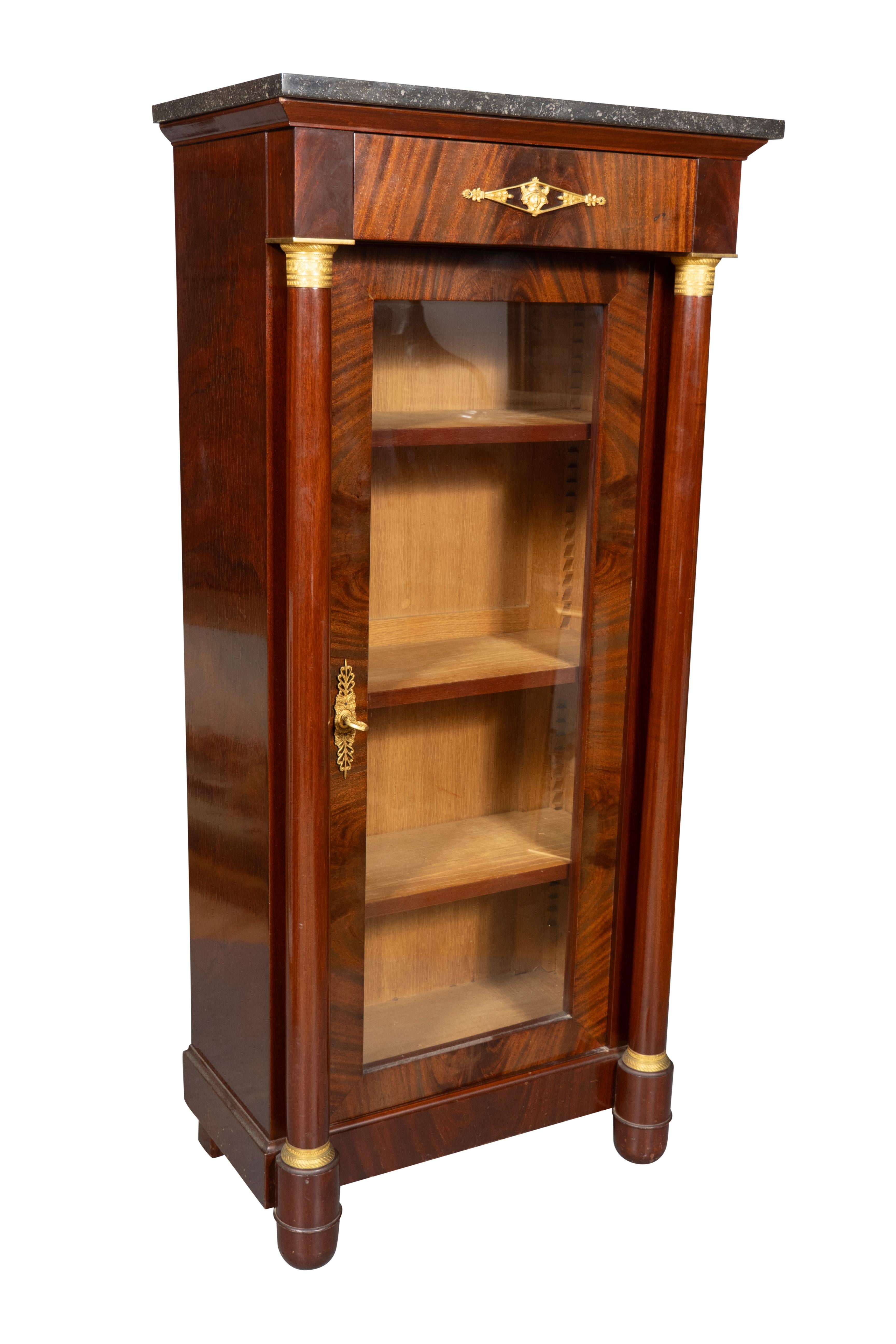 With a rectangular grey and white marble top over a drawer and glass cabinet door flanked by columns, enclosing three shelves. Has key.