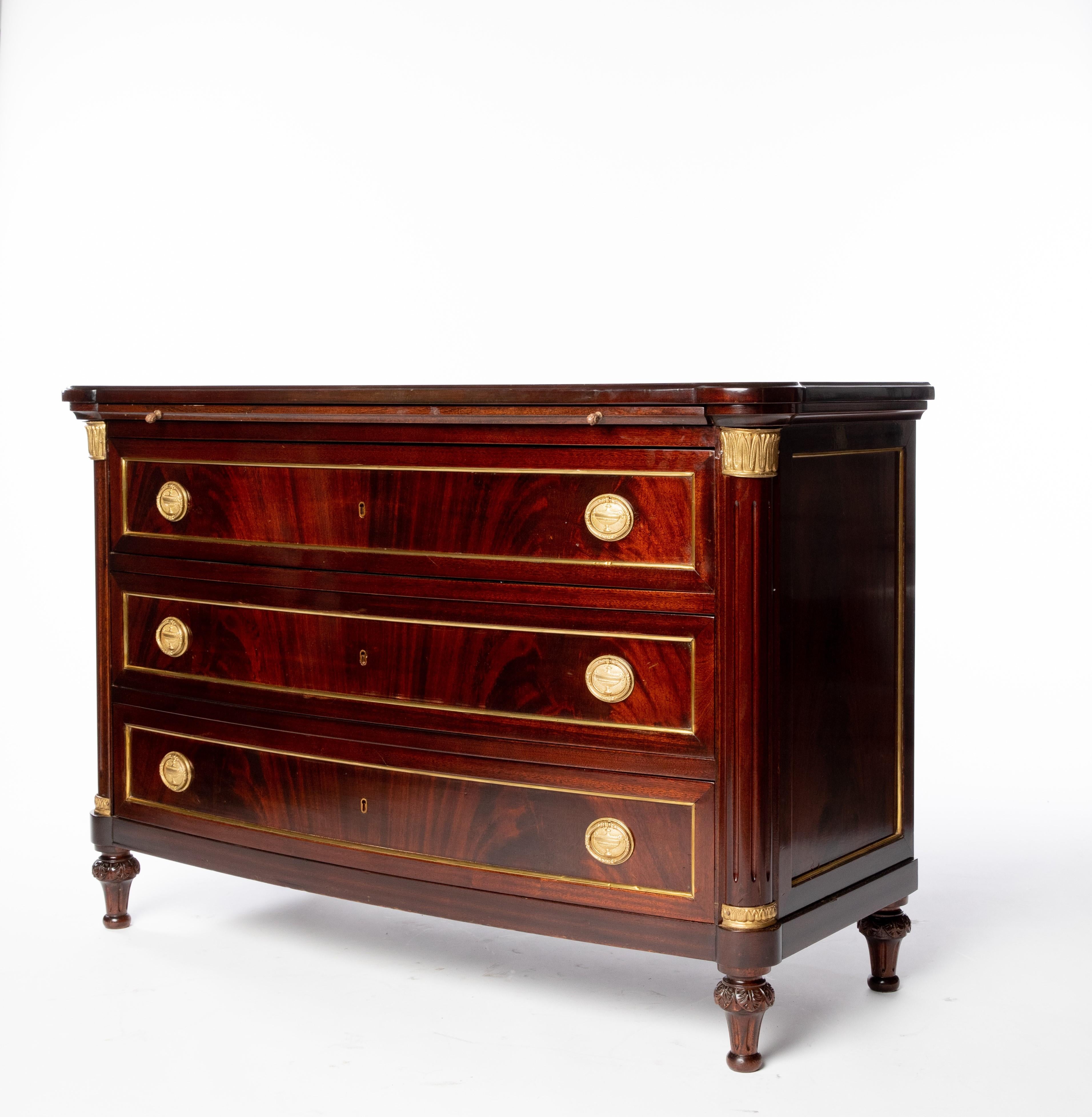 Empire style mahogany commode, early 20th c., bow front case fitted with pull-out leather brushing slide, over three drawers, flanked by fluted corner posts, rising on tapered legs.