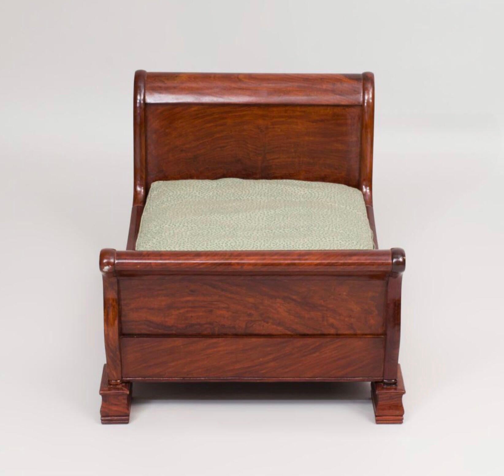 The diminutive mahogany sleigh bed with green and white upholstery.