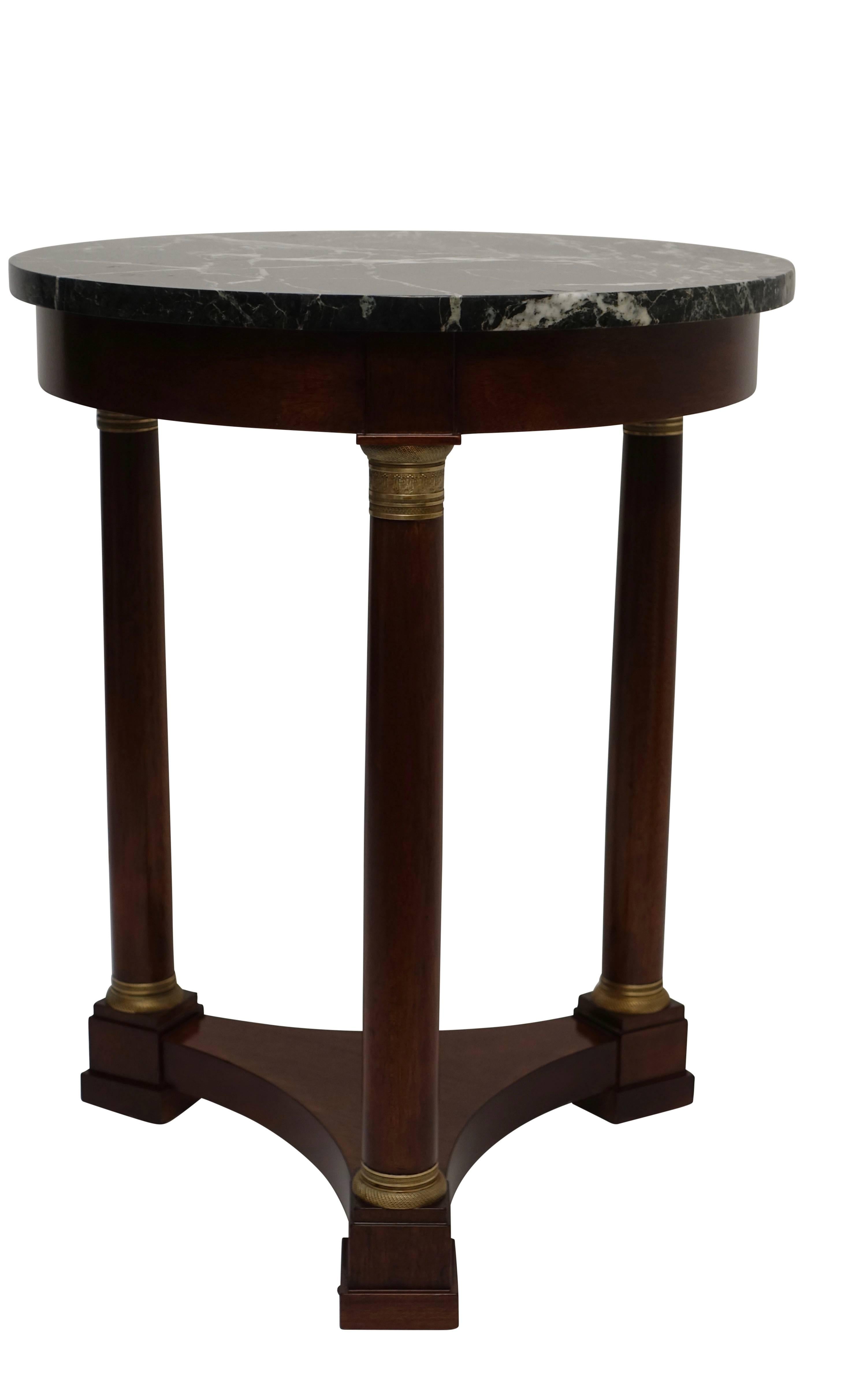 An Empire style mahogany side table with dark green marble top and brass-mounted columns.