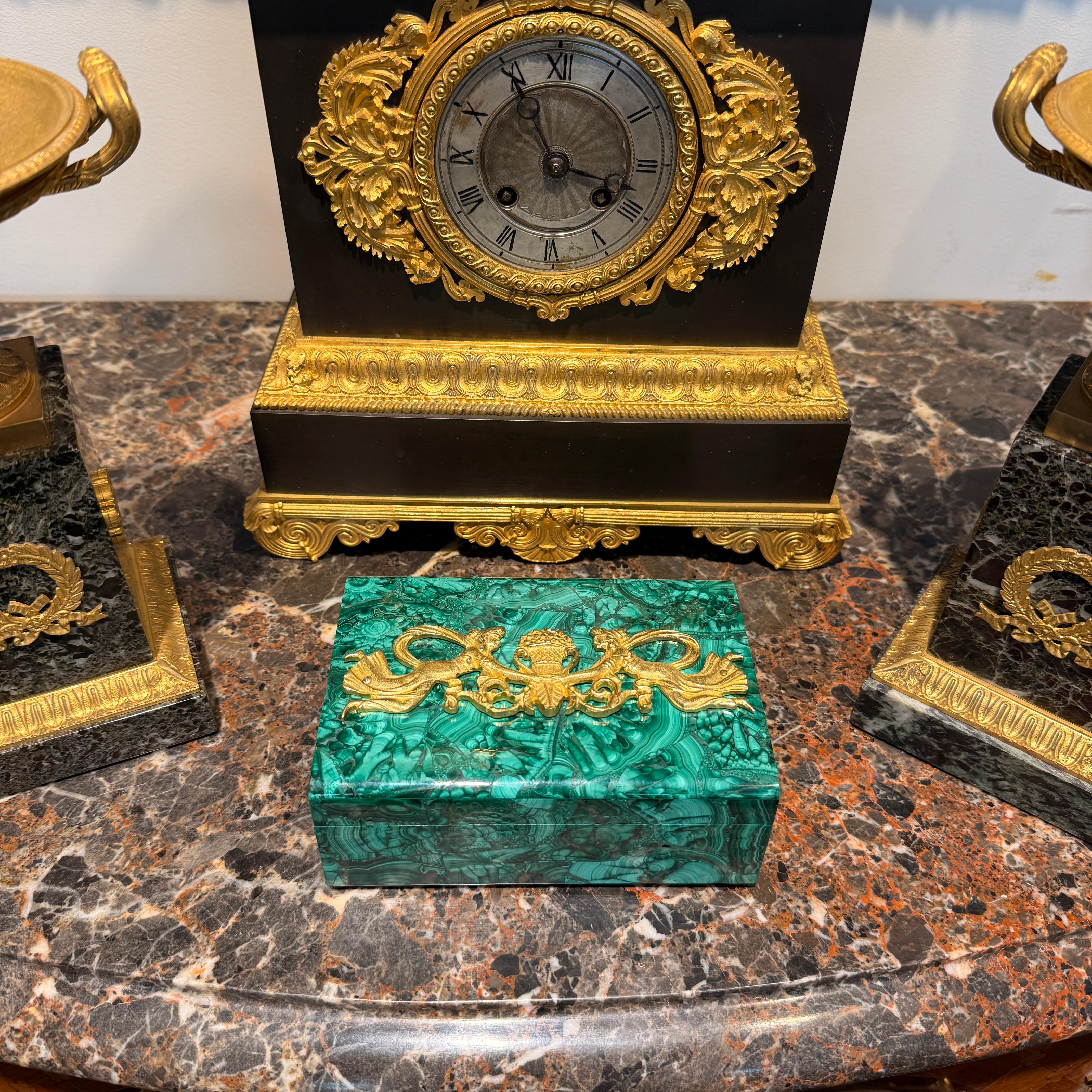 Empire Style Malachite and Gilt Bronze Box, 19th Century, Depicting Two Muses Holding a Cornucopia
This 19th-century malachite box perfectly embodies the elegance and grandeur of the Empire style. Resting on a rectangular base of richly veined