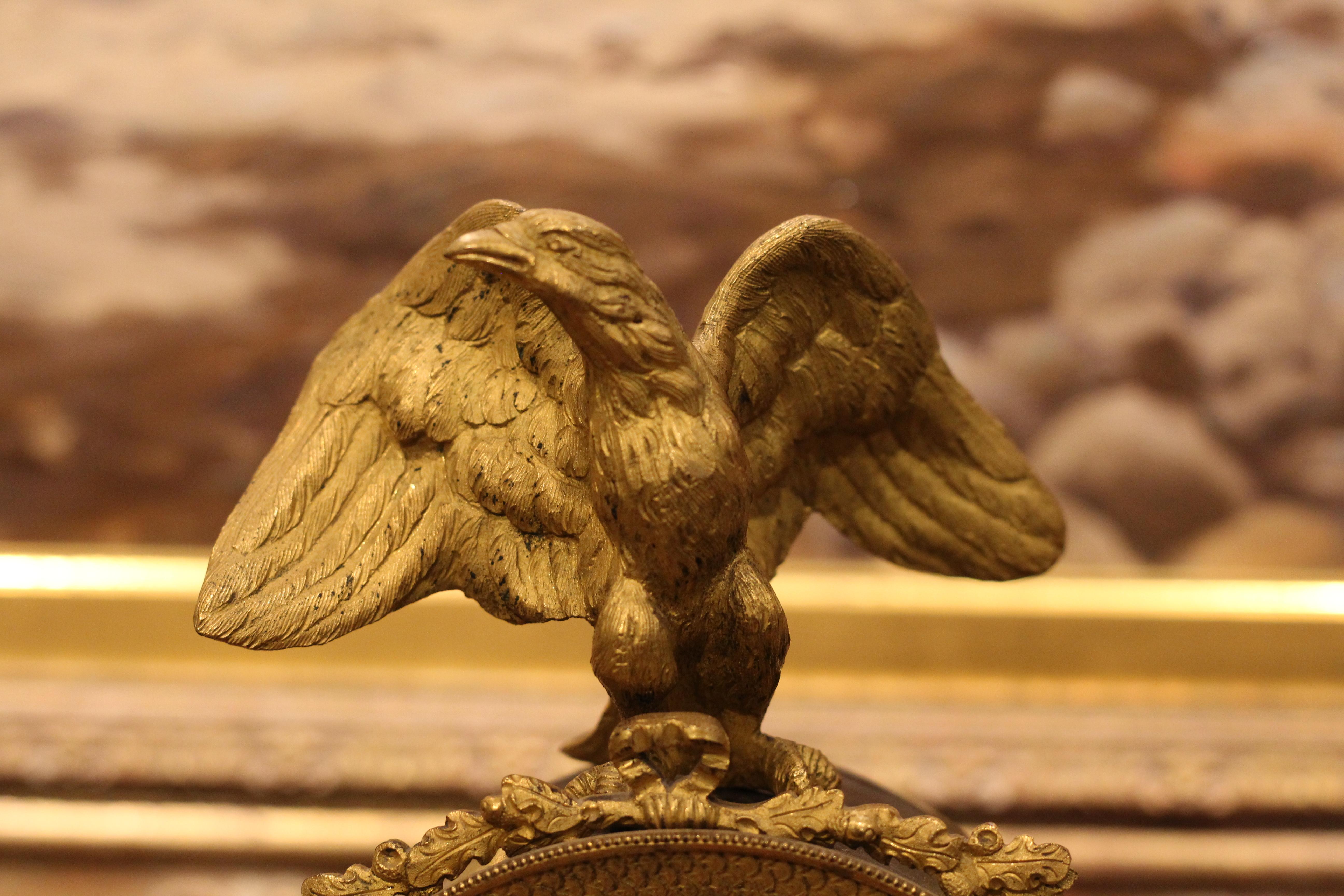 Empire style mantle clock with gilt bronze and bronze adornments of an eagle and cherubs,
circa 1820-1840.