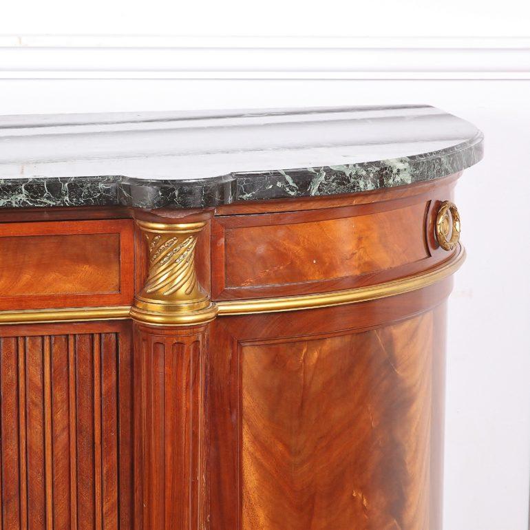 An excellent-quality French mahogany and marble top buffet, with curved quarter-round side doors and drawers, the centre with a pair of reeded herringbone-veneer doors, below two centre drawers, the whole embellished with finely-cast gilt bronze