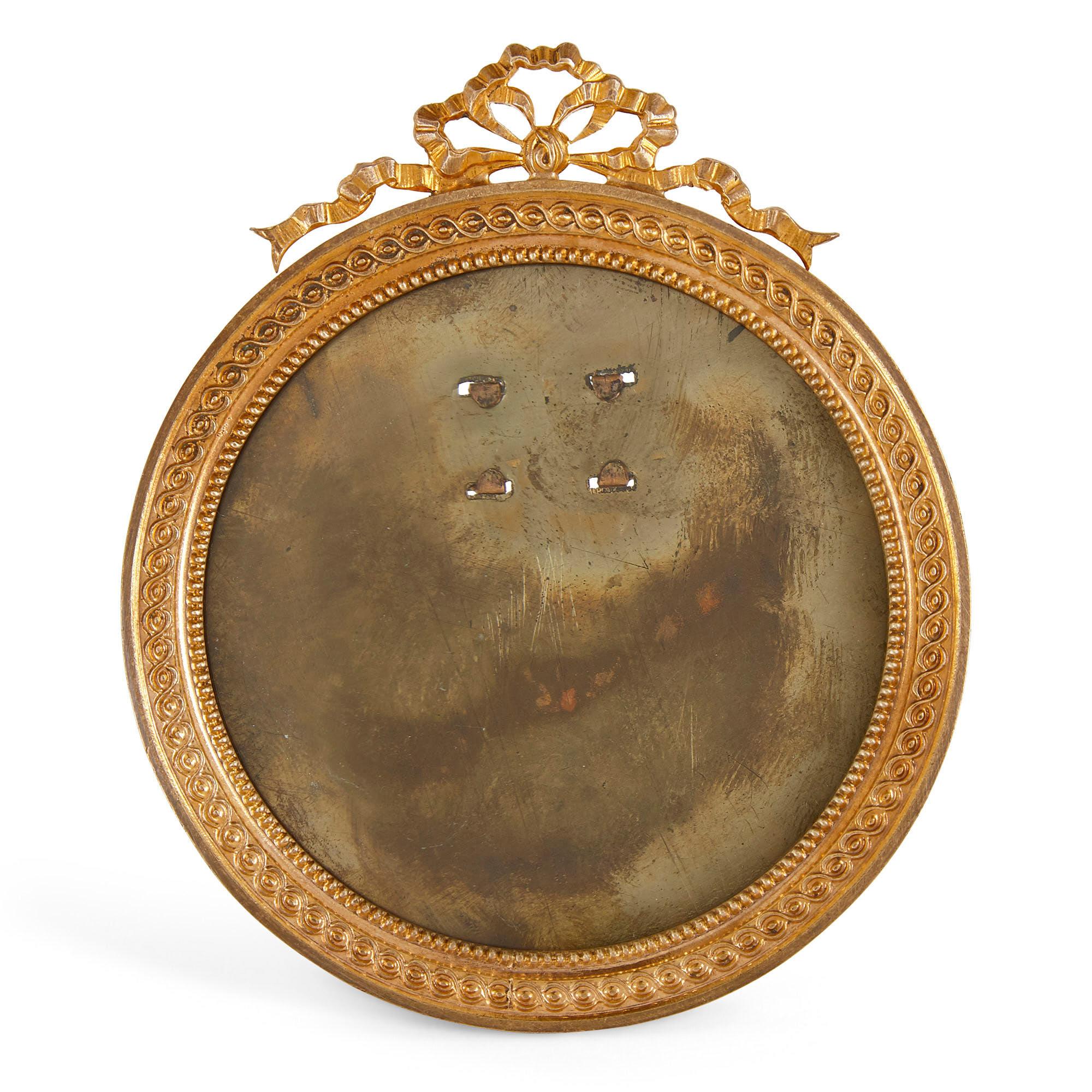 Empire style miniature gilt bronze picture frame
French, early 20th century
Measures: Height 9cm, width 8cm, depth 0.5cm

This beautiful miniature picture frame is designed in the French Empire style. The frame is circular in form, moulded with