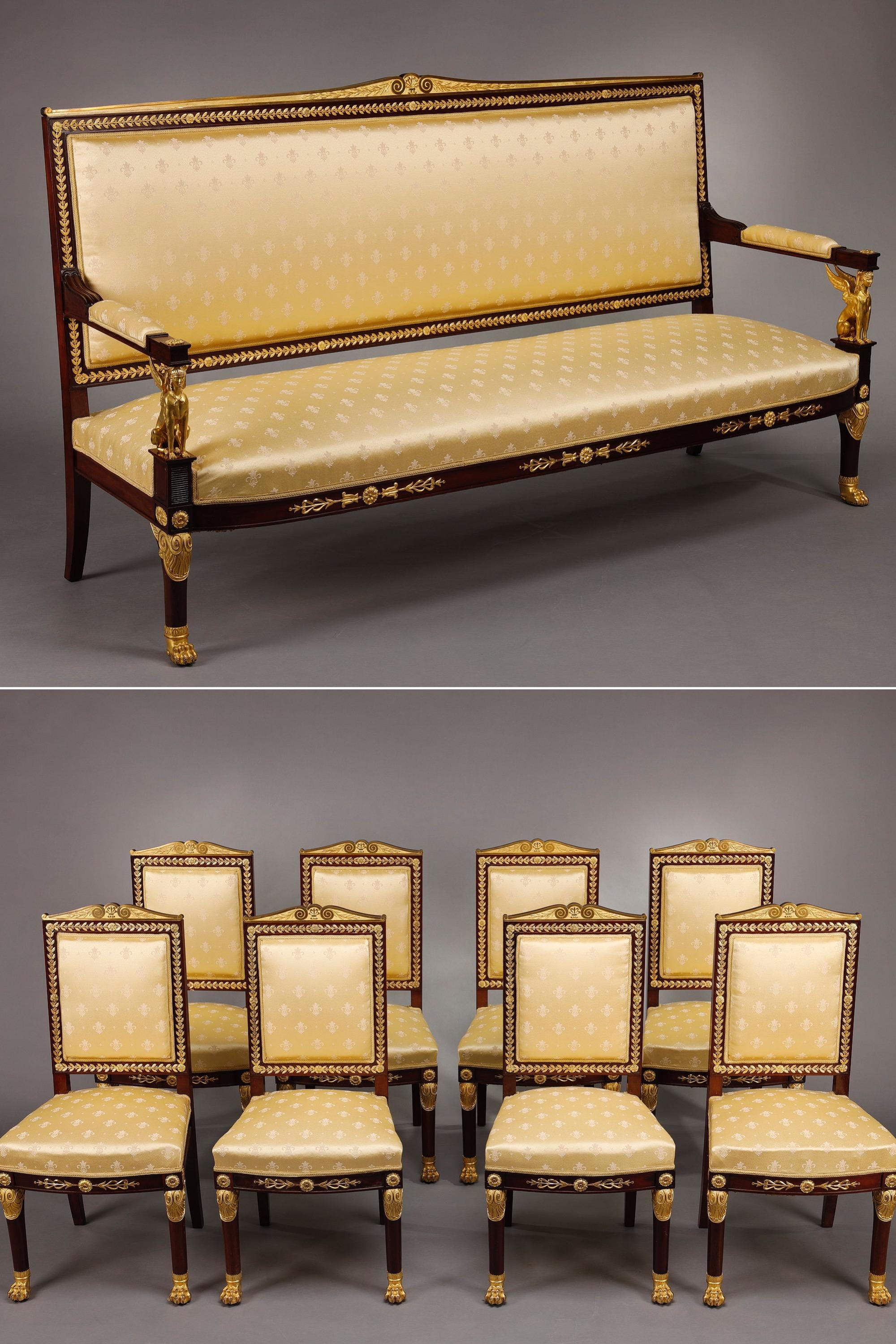 An imposing Empire-style salon comprising a mahogany sofa and eight chairs. They are richly adorned with gilded bronzes, with a rectangular pedimented back decorated with laurel leaf friezes, scrolls, rosettes, sphinxes and claw feet. Refurbished