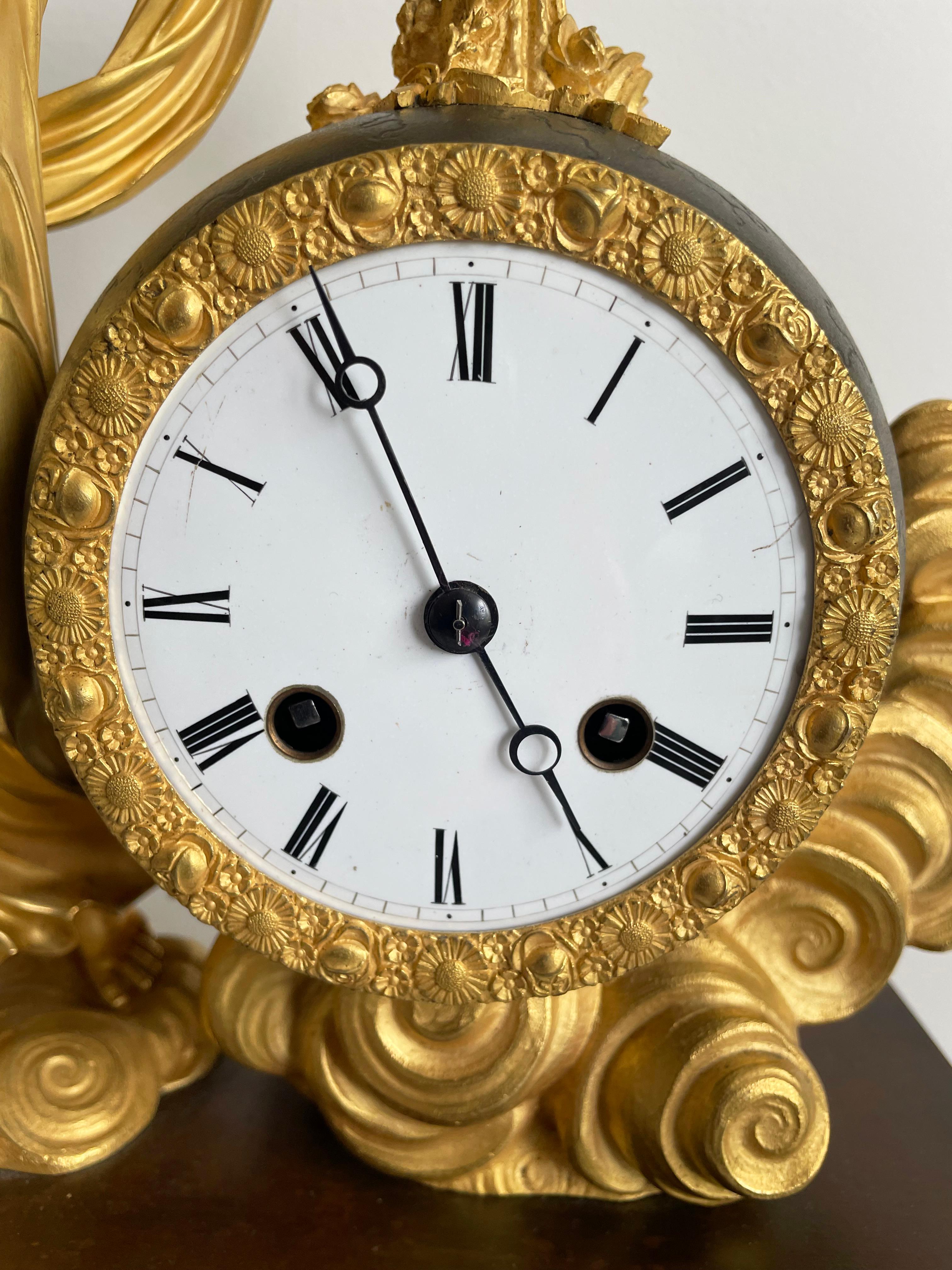 French Empire table clock by Cleret, Paris, movement by Pierre-César Honoré Pons.  The case in gilded and patinated bronze, circa 1825.

The bronze base is decorated with a broad floral frieze with a central urn and two doves above a gilt floral