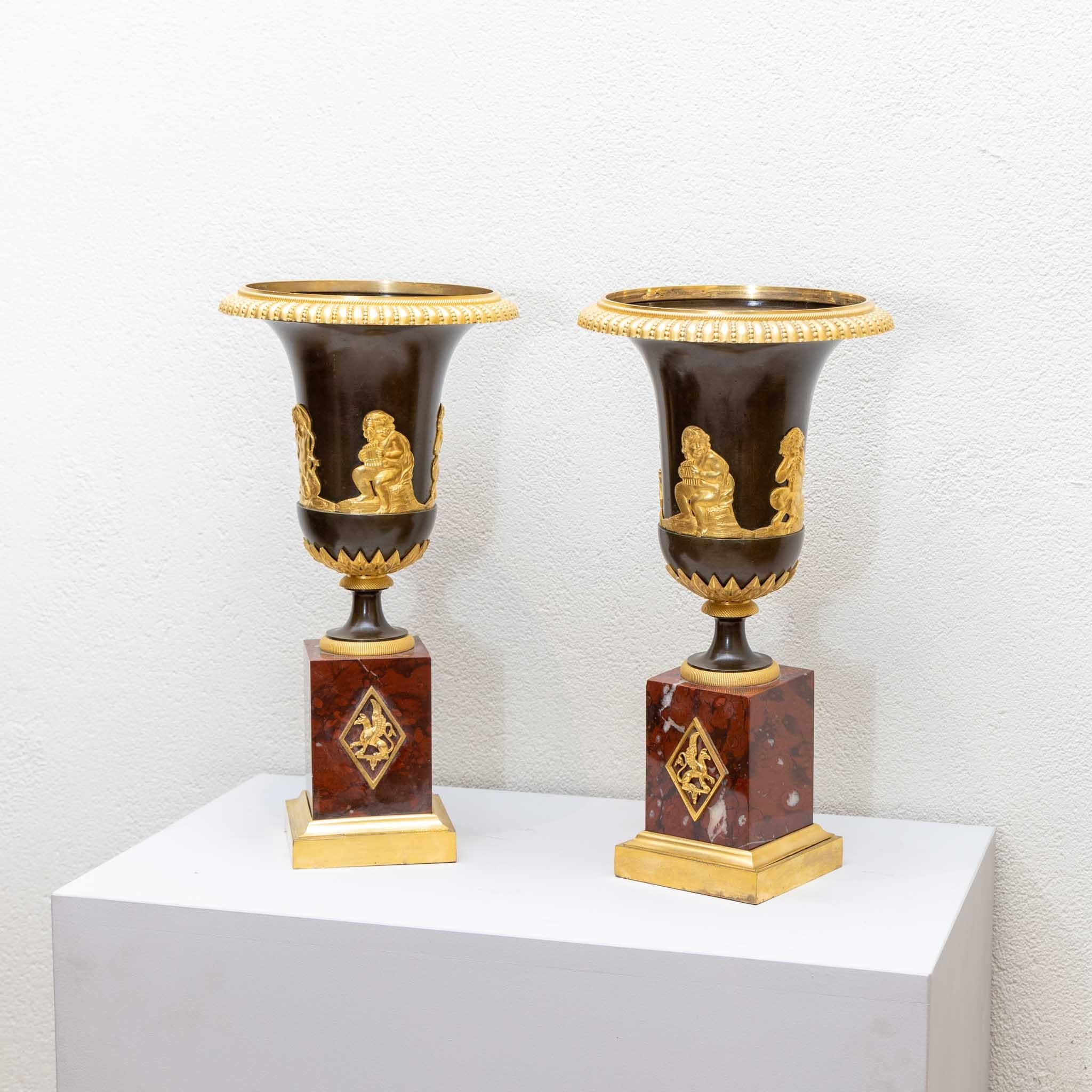 Ein Paar Empire-Vasen auf Sockeln aus rotem Marmor mit feuervergoldeten Bronzebeschlägen in Form von kleinen Satyrn und Putten. (Maße Sockel: 10 x 10 cm).