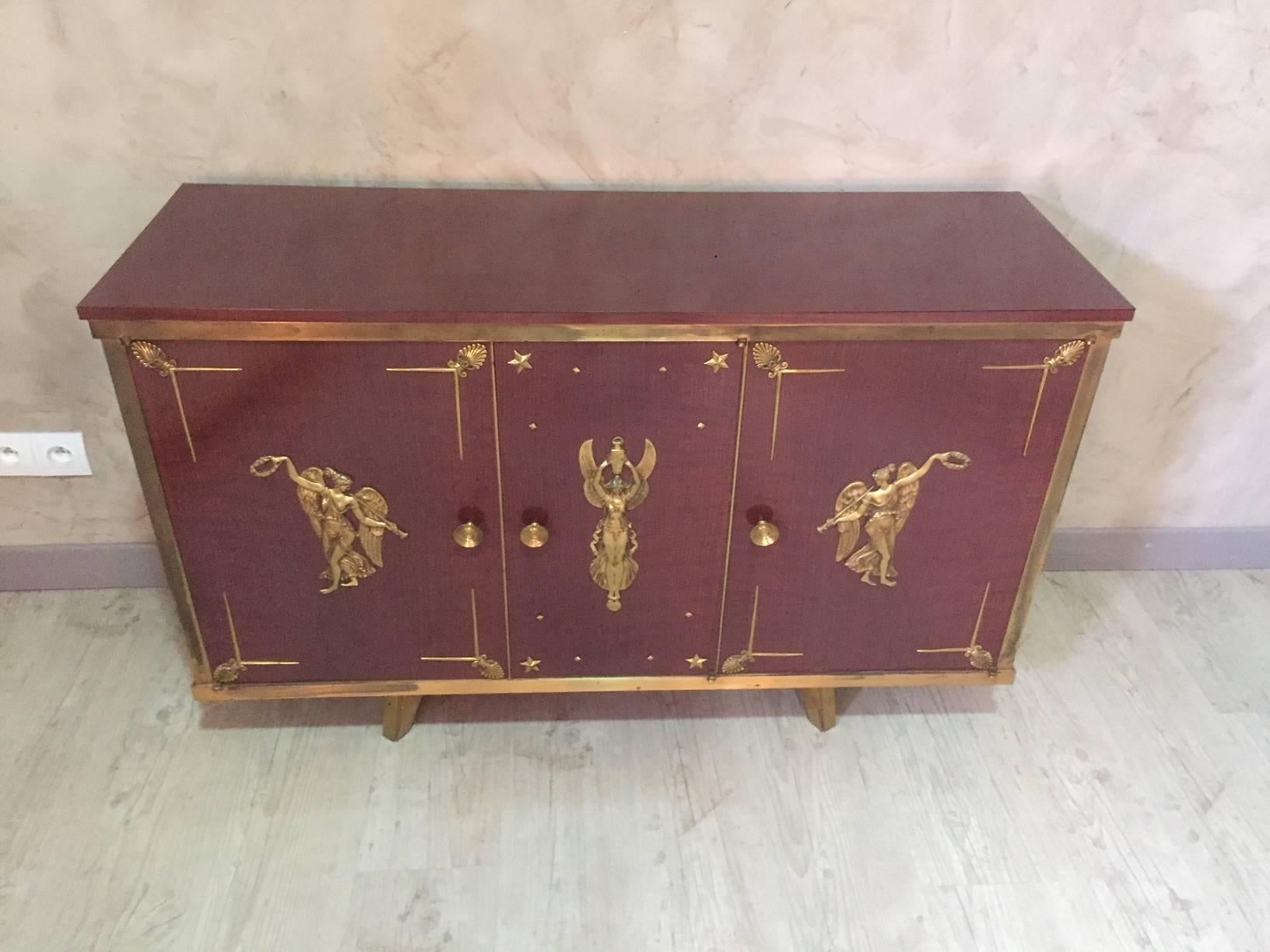 Empire veneered mahogany and gilded brass enfilade, 1950s. Rare model. Three doors.
Removable top. Nice characters brass work. Asymmetrical brass feet.