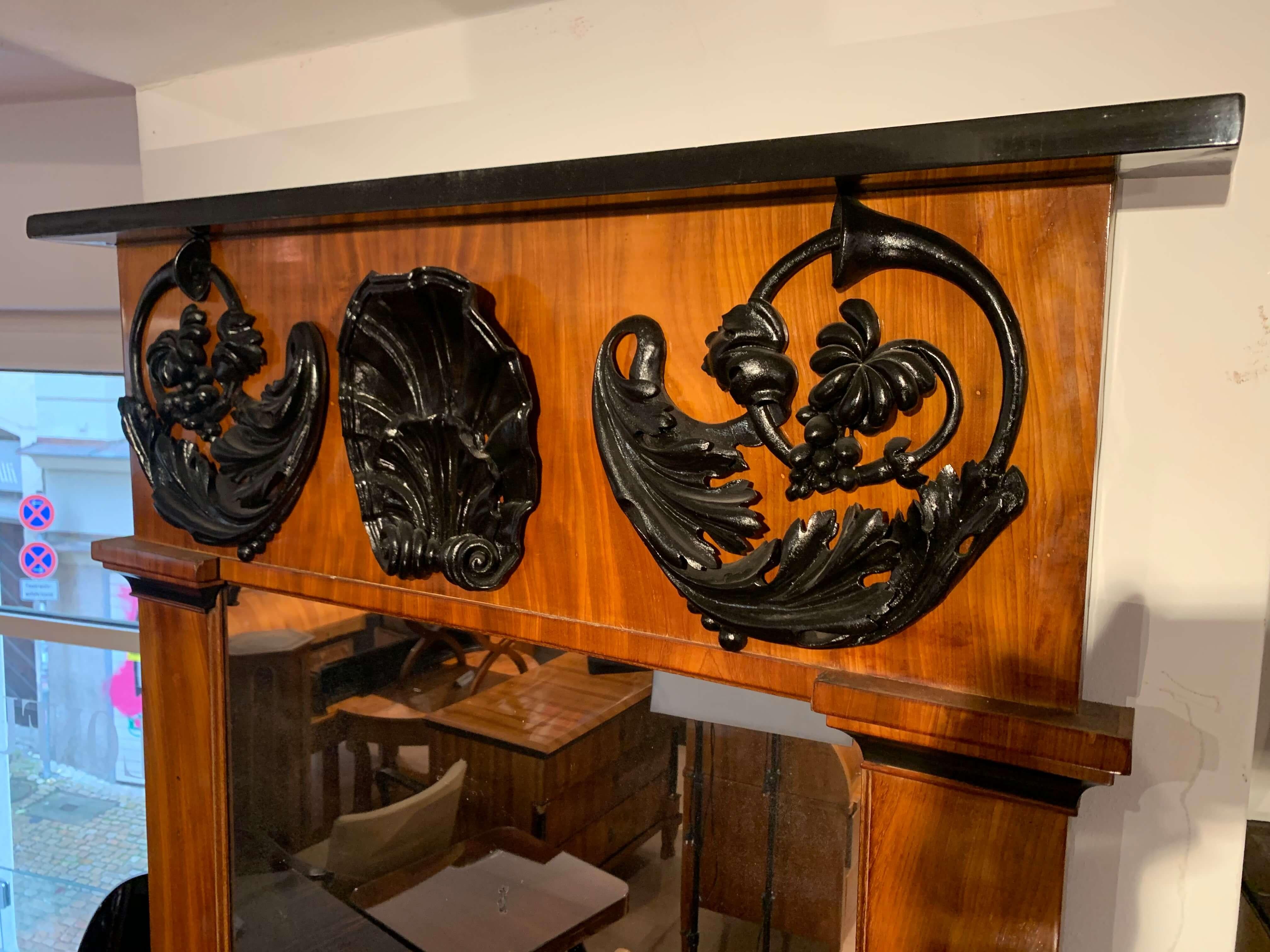 Beautiful neoclassical Empire wall mirror, bright mahogany, carved ebonized (blackened) decor, South Germany, circa 1810.

The wood is mahogany veneer and solid wood, which has been bleached and stained for a brighter cherry tree color tone.