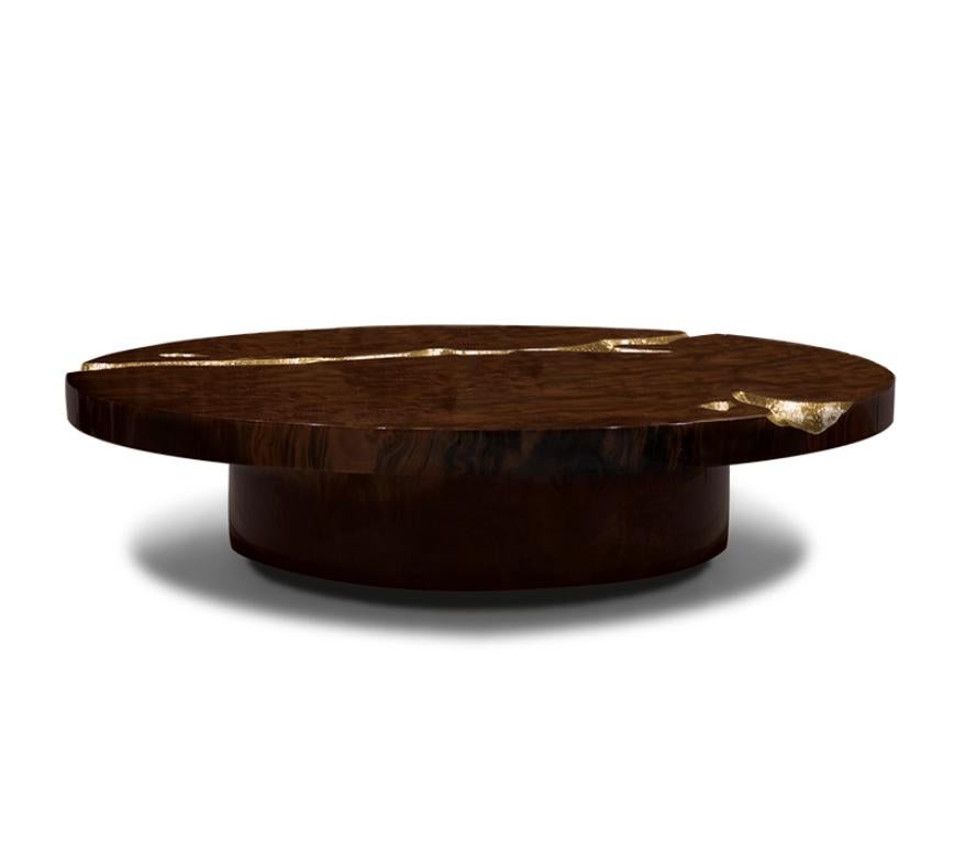 A Contemporary Empire Center Table by Boca do Lobo, elegant round center table built from mahogany wood and features an exquisite polished brass surface detail, its cracks are hand-carved and inserted through polished brass sheets, which are hand