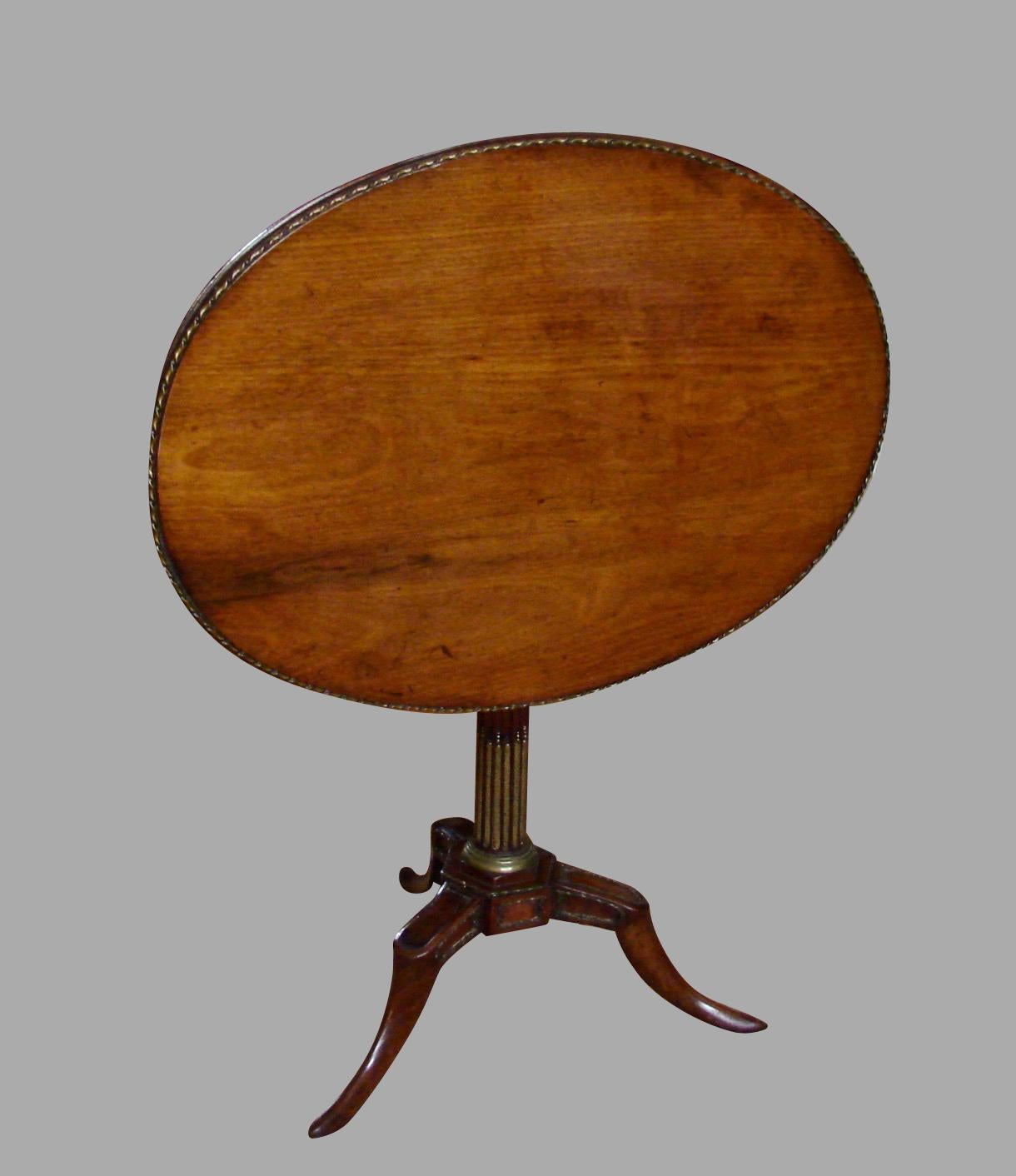 A pretty French metal-mounted walnut Empire style tilt-top tea table, the oval top with an applied rope twist metal edge supported on a reeded standard terminating in a tripod base and slipper feet, circa 1820.