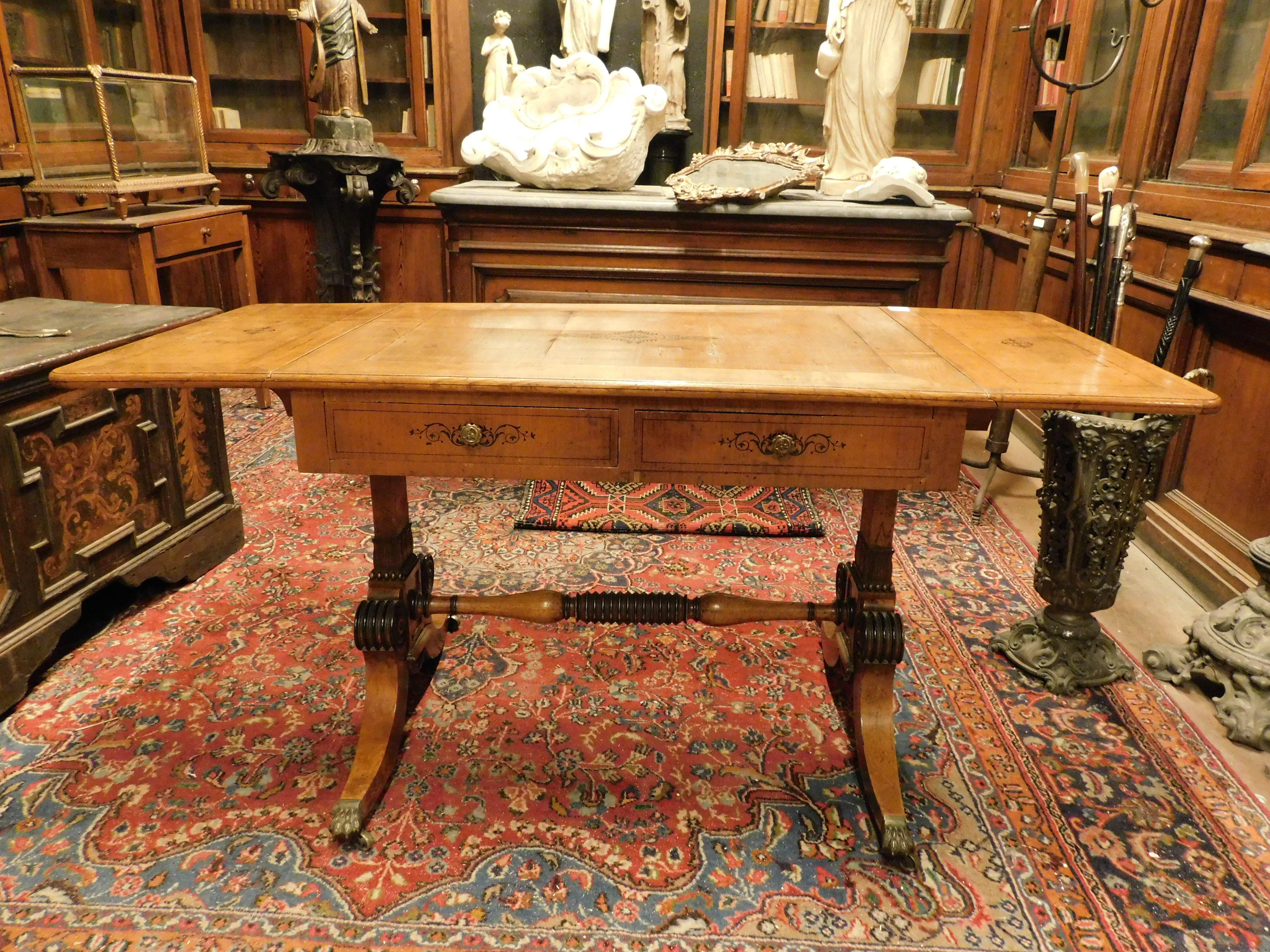Antico scrittoio Impero in ciliegio chiaro, con alette laterali sollevabili, presenta intarsi ebanizzati con decorazioni floreali e di foglie, sia sul piano che sui due cassetti e sul retro, Le gambe sono unite da una traversa tornita e terminano