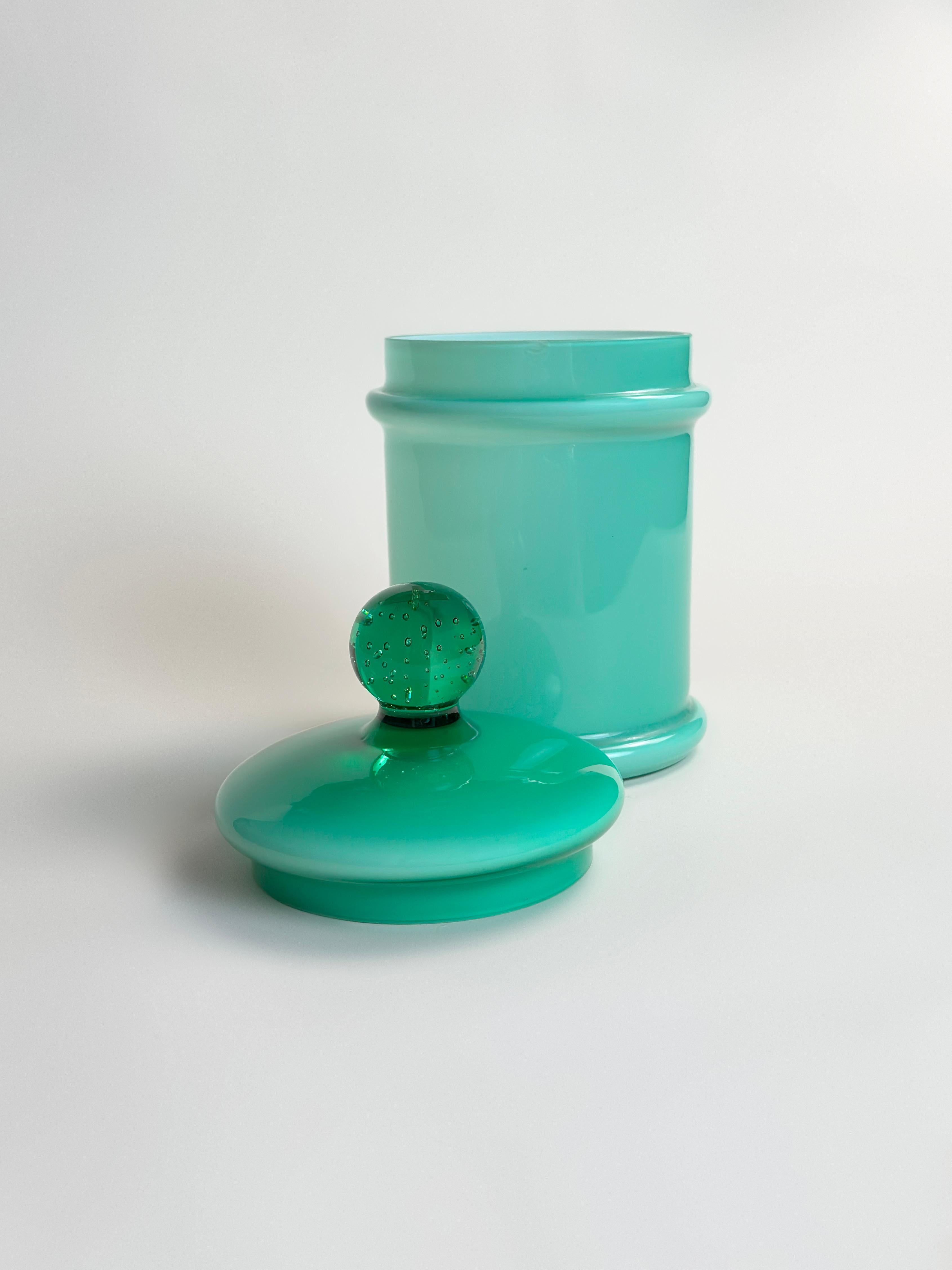 Un caratteristico barattolo da farmacia in vetro verde di Empoli, opera di Carlo Moretti, realizzato in Italia intorno agli anni '70. Questo vaso vintage italiano presenta un corpo in vetro verde turchese saturo, soffiato in vetro incamiciato con