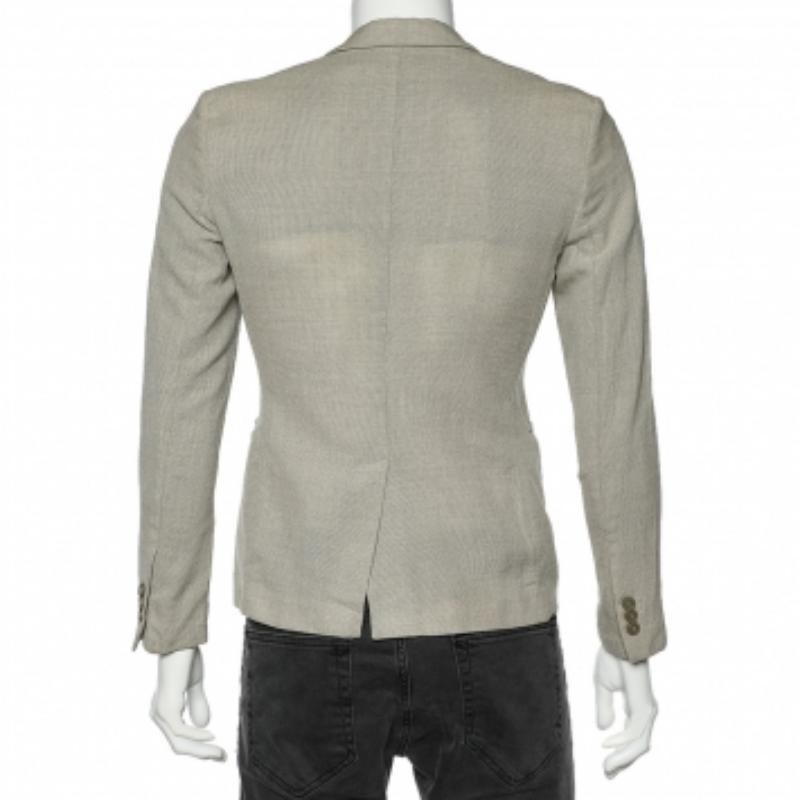 Derrocha encanto y sofisticación con este blazer de la Casa Emporio Armani. Está confeccionado con tejido de lana beige texturizado. Presenta mangas largas, un detalle frontal abotonado y tres bolsillos exteriores. Mejora tu colección de ropa formal