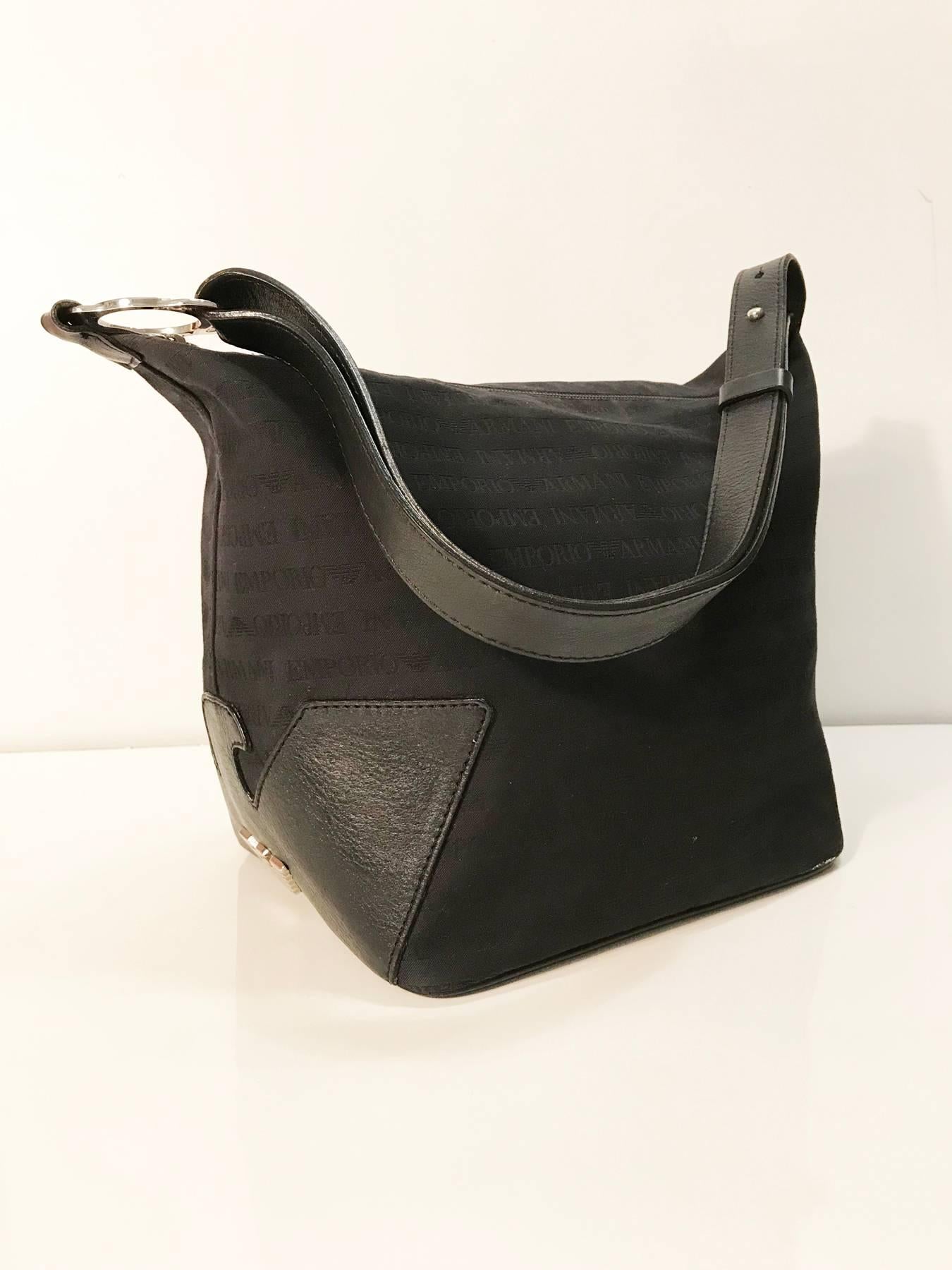 This Emporio Armani hobo bag is kind of a square sack, it is made of black canvas with Armani monogram pattern. The bottom and half of one side is made of quality black leather in great conditions, the leather cut the logo on the side and on top  of