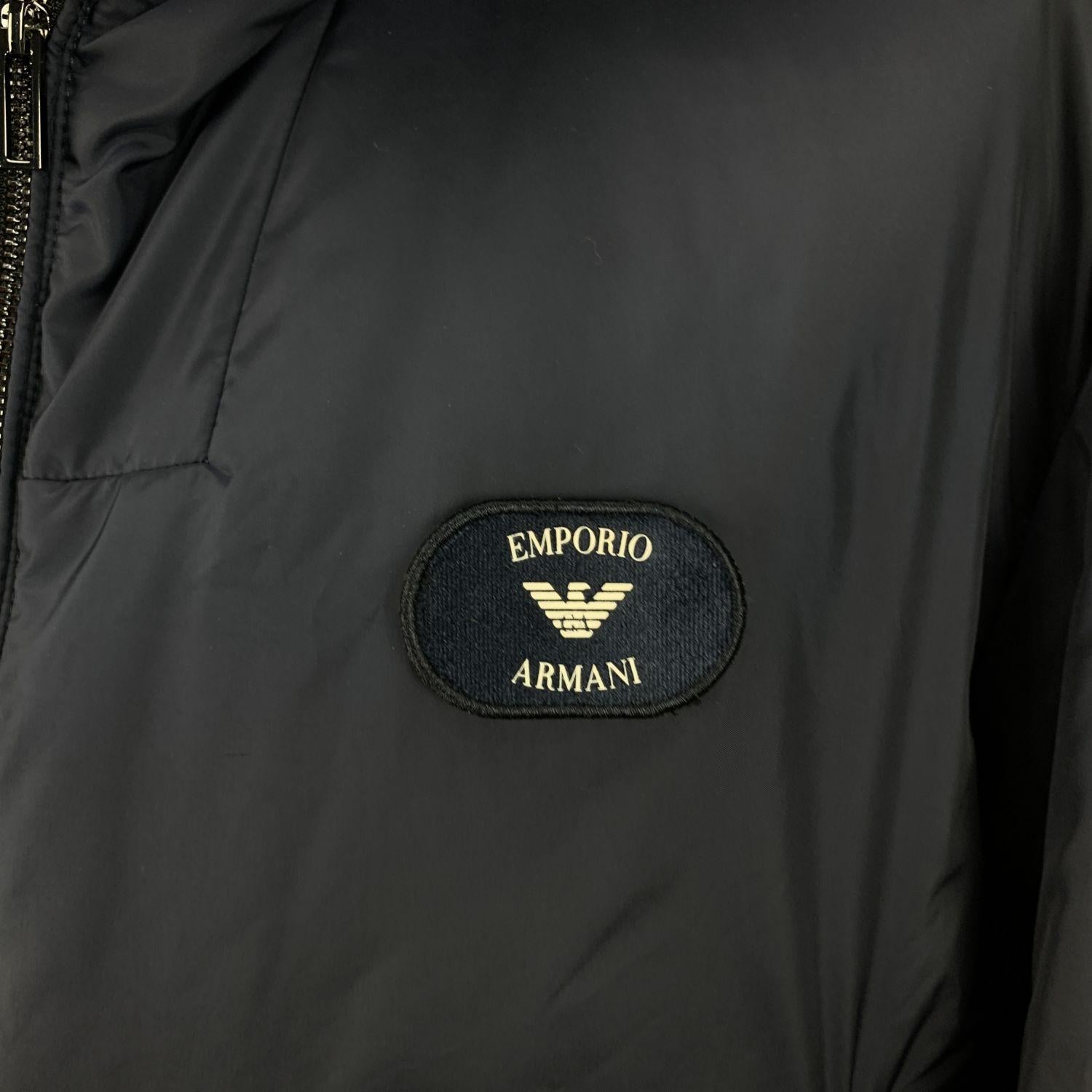 Emporio Armani blue padded hooded jacket. Built-in suspenders. Polyester padding. Front zip closure. Composition: 100% Polyester. 2 zip pockets on the waist. Size: XXL (The size shown for this item is the size indicated by the designer on the