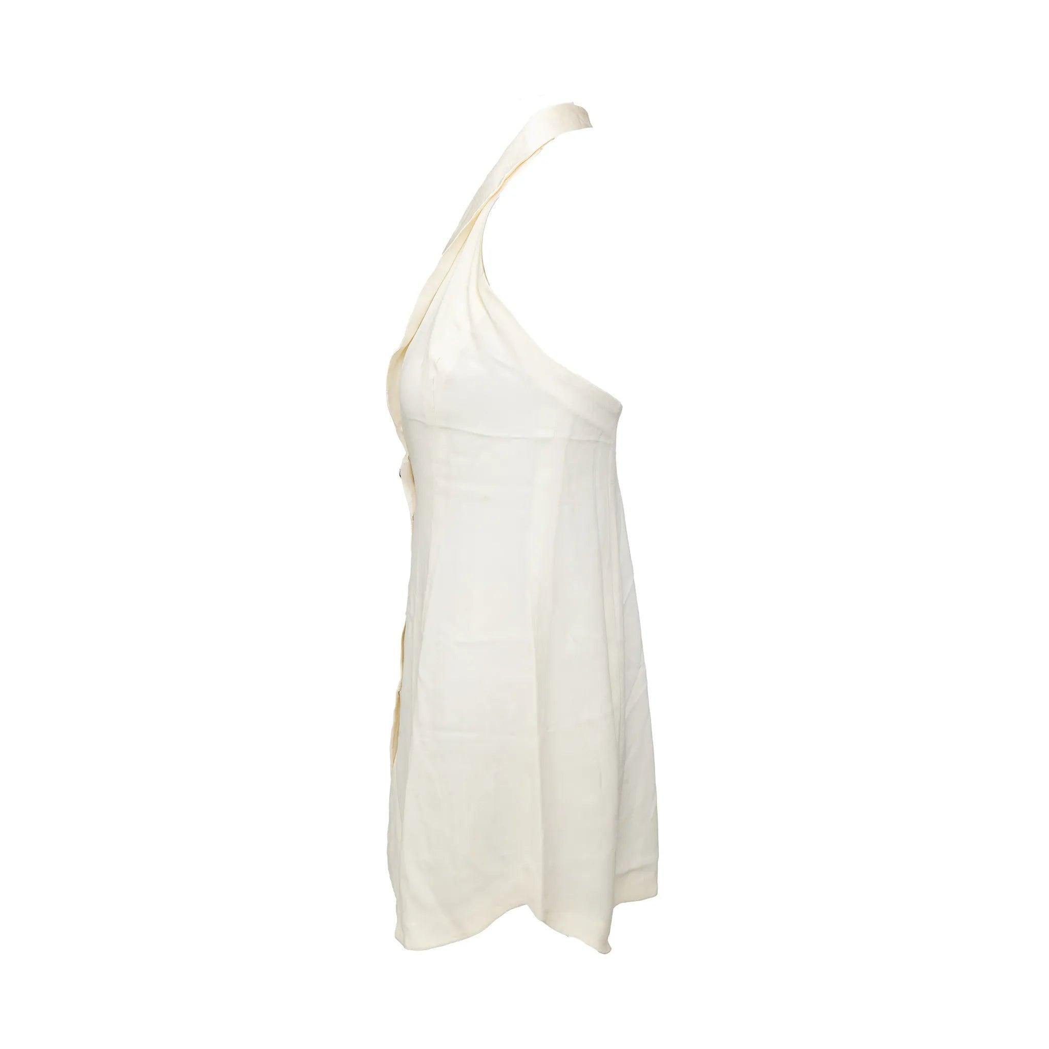 Minivestido Emporio Armani forrado de color blanco roto con cuello halter, silueta fluida, media espalda abierta y cierre frontal con botones de pedrería.
 Observaciones: Falta la etiqueta de composición. Hay algunas pequeñas manchas. 
 Medidas:
