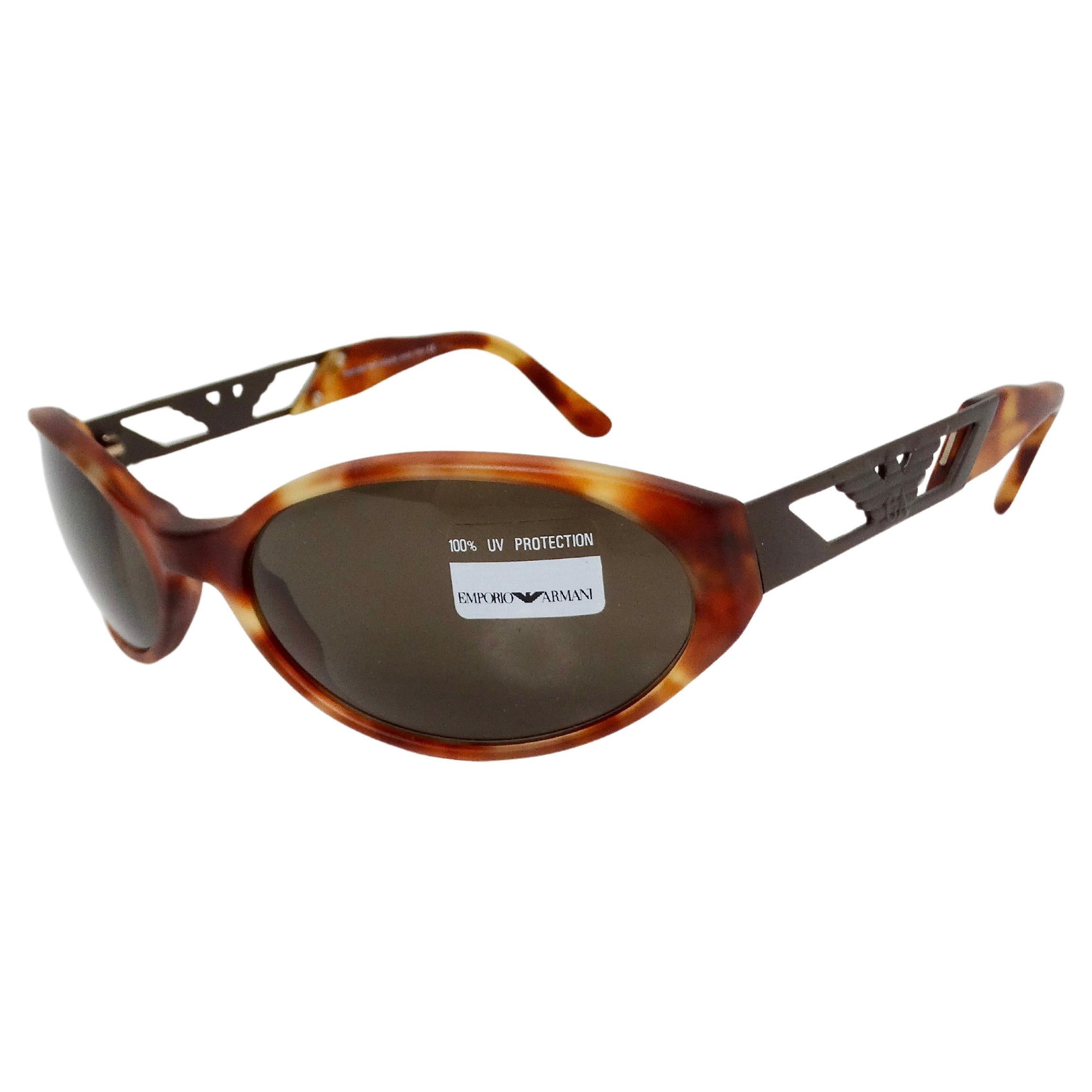 The Emporio Armani Matte Tortoise Oval Shield Sunglasses circa 1990s embody a unique blend of contemporary design and classic elegance. Featuring a light tortoise shell color, these sunglasses serve as a versatile accessory that enhances any outfit