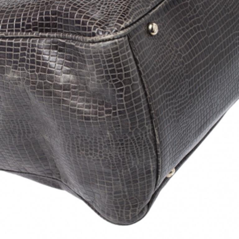 Diese Tasche von Emporio Armani ist aus krokodilgeprägtem Leder gefertigt. Er hat einen schönen olivgrünen Farbton, der die Patina des Äußeren unterstreicht. Sie verfügt über eine Außentasche auf der Vorderseite, zwei Henkel, ein Markenzeichen, ein