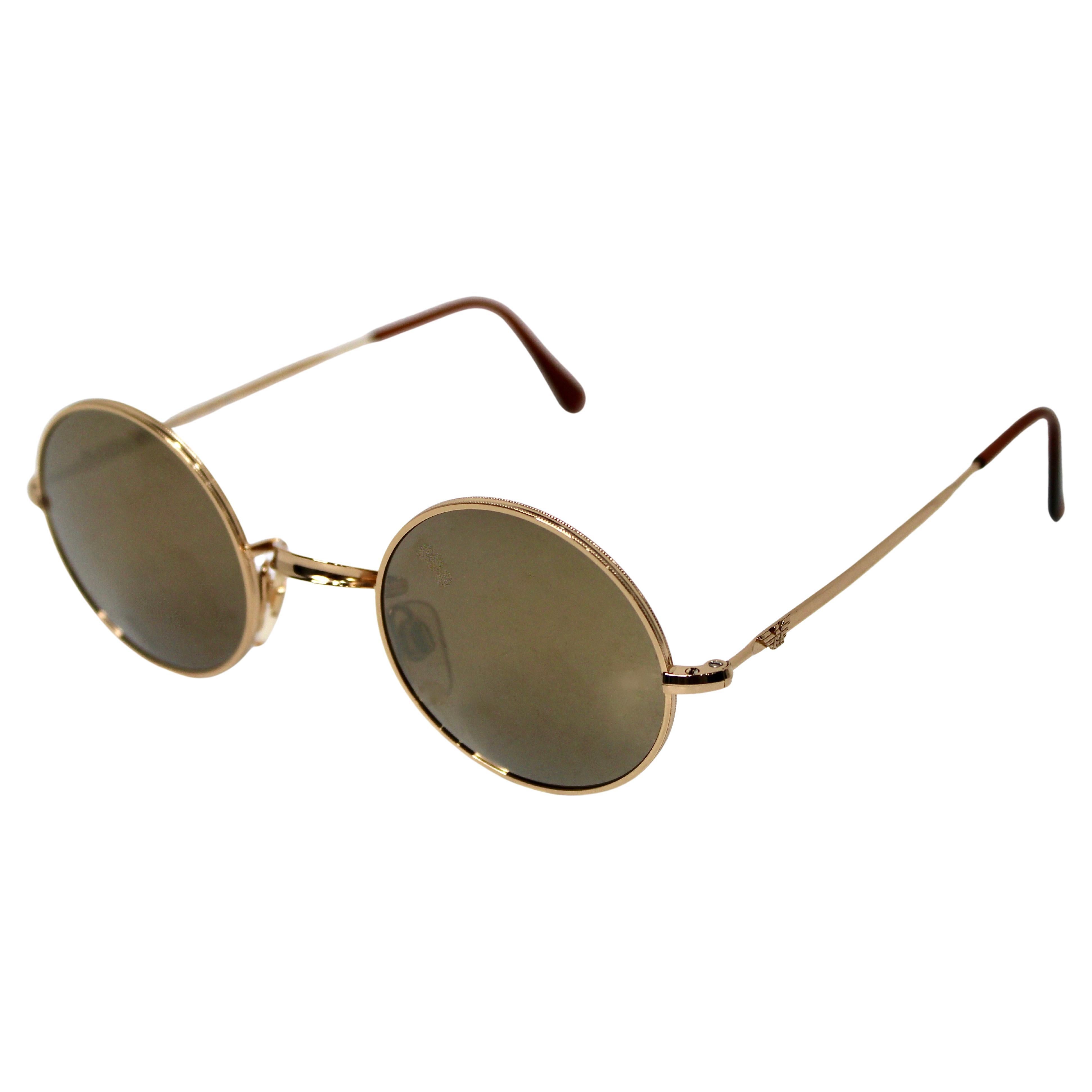 Ces lunettes de soleil vintage Emporio Armani des années 1990 présentent un design intemporel et sophistiqué caractérisé par des verres ronds miroitants et des montures élégantes en métal doré. Les verres réfléchissants ajoutent une touche de