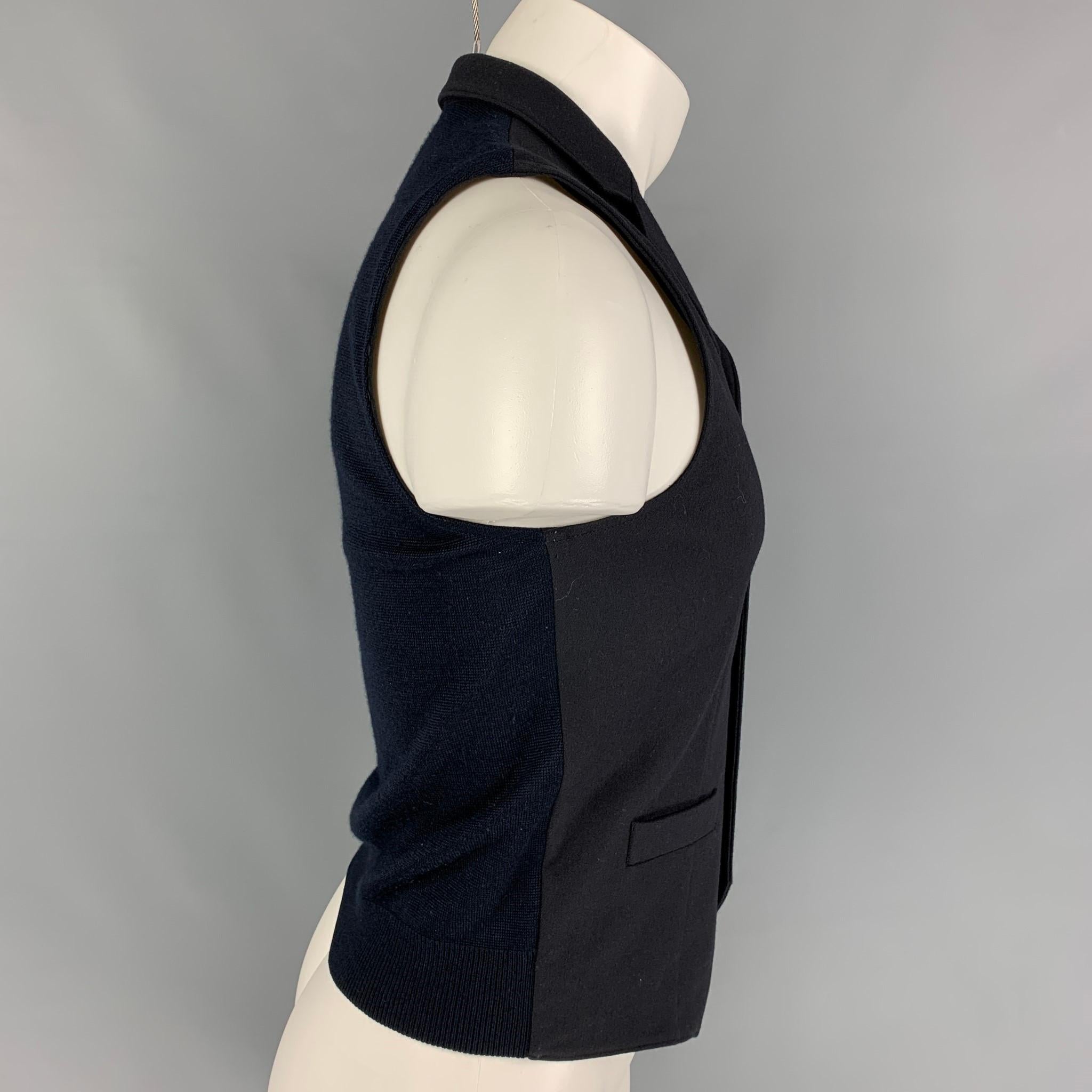 EMPORIO ARMANI vest comes in a navy wool blend featuring a knitted back, notch lapel, and a snap button closure. 

Very Good Pre-Owned Condition.
Marked: 44

Measurements:

Shoulder: 12.5 in.
Chest: 34 in.
Length: 22 in. 