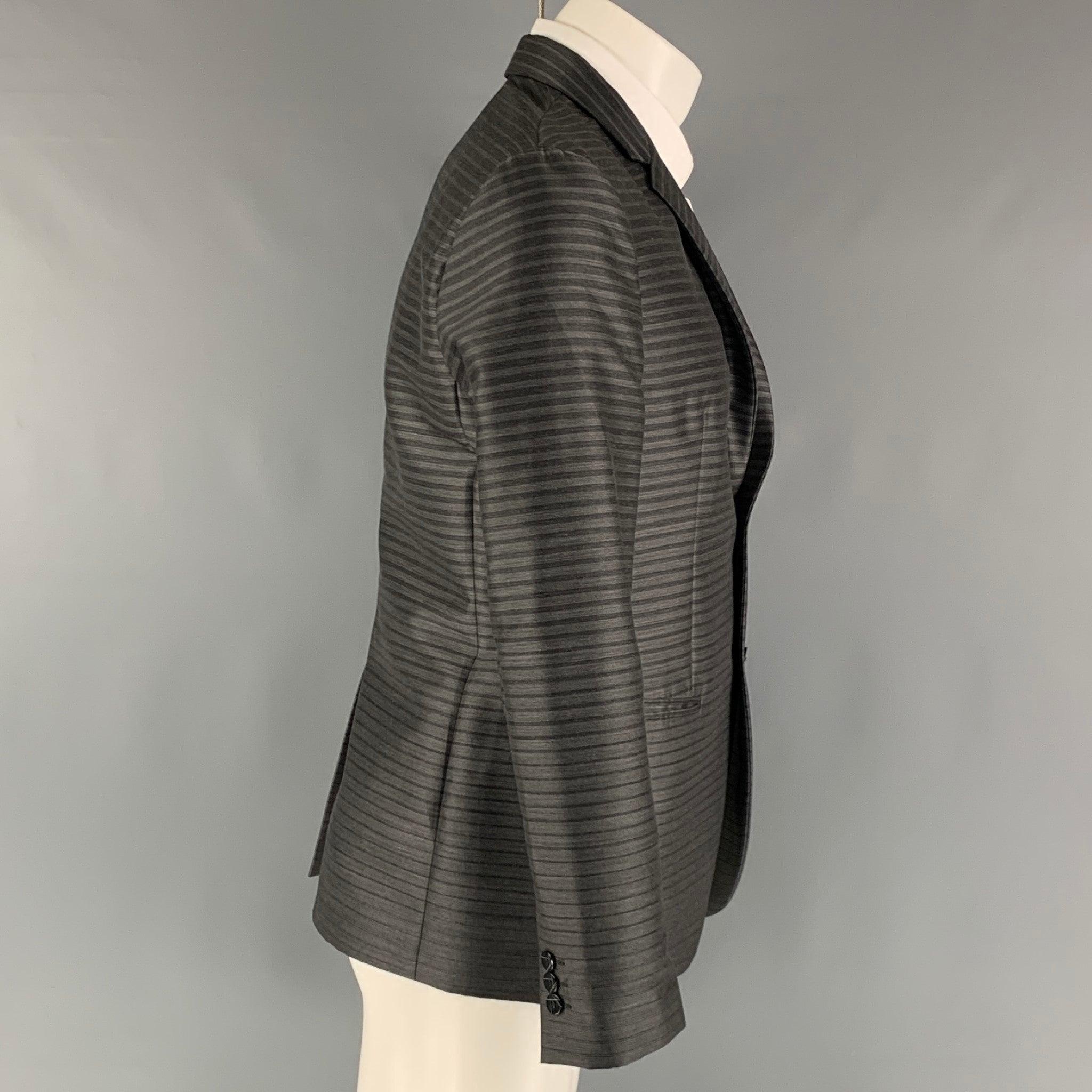 EMPORIO ARMANI sport coat comes in a grey and charcoal stripped wool blend woven material full liner featuring a notch lapel, welt pockets, single back vent, and a two button closure. Made in Italy. Excellent Pre-Owned Condition. 

Marked:   48