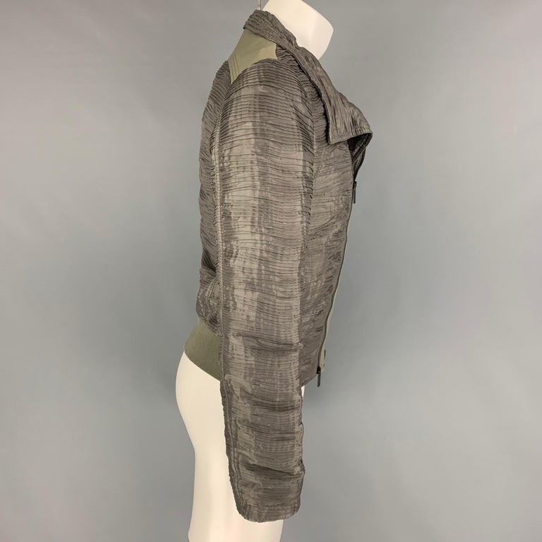 EMPORIO ARMANI jacket comes in a olive ruched polyester featuring a leather panel, high collar, ribbed hem, slit pockets, and a asymmetrical zip up closure. 

Very Good Pre-Owned Condition. Light mark at shoulder. Due to contrast of the backdrop the