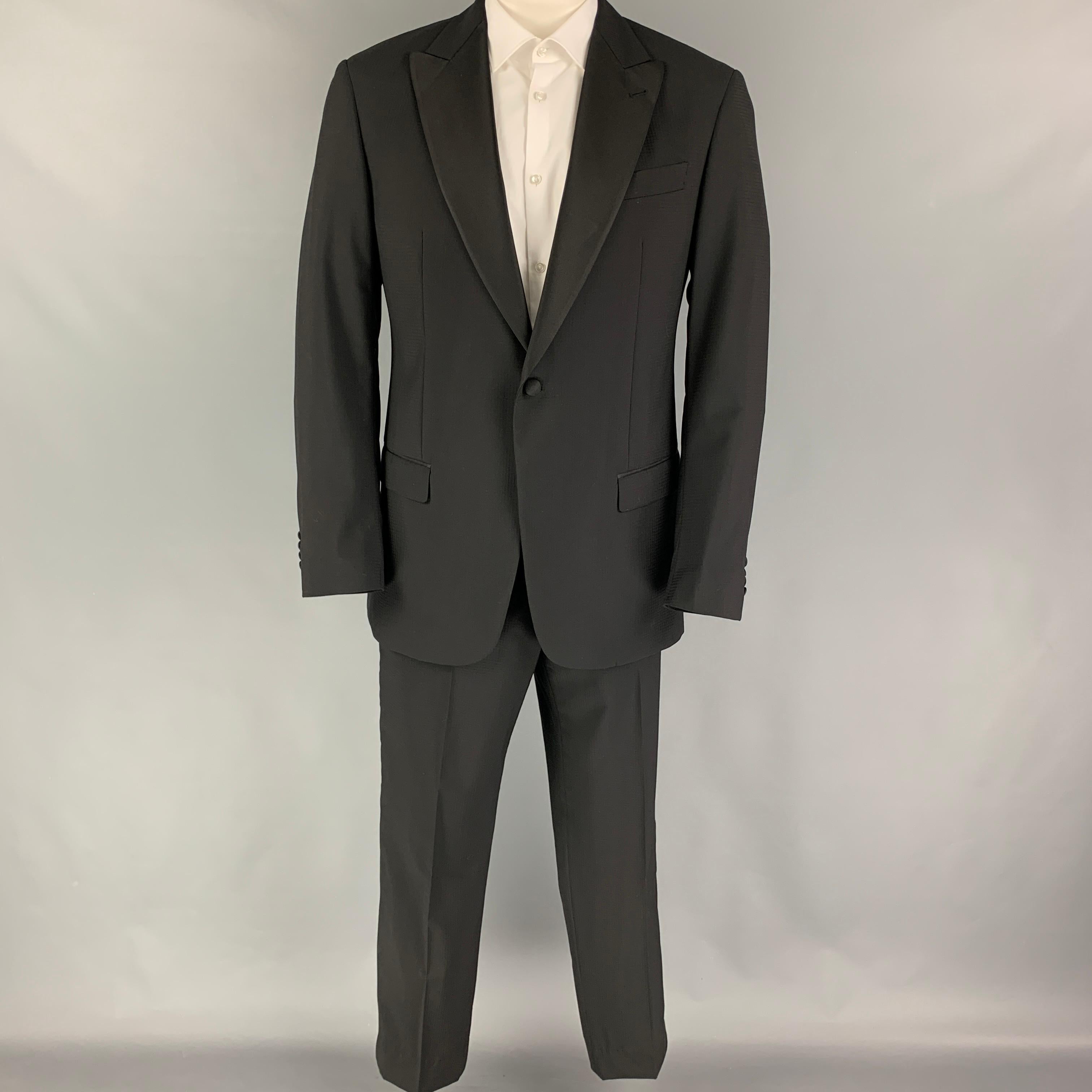 EMPORIO ARMANI suit comes in a black grid material with a full liner and includes a single breasted, single button sport coat with a peak lapel and matching flat front trousers.

Excellent Pre-Owned Condition. Fabric tag removed.
Marked: Size tag