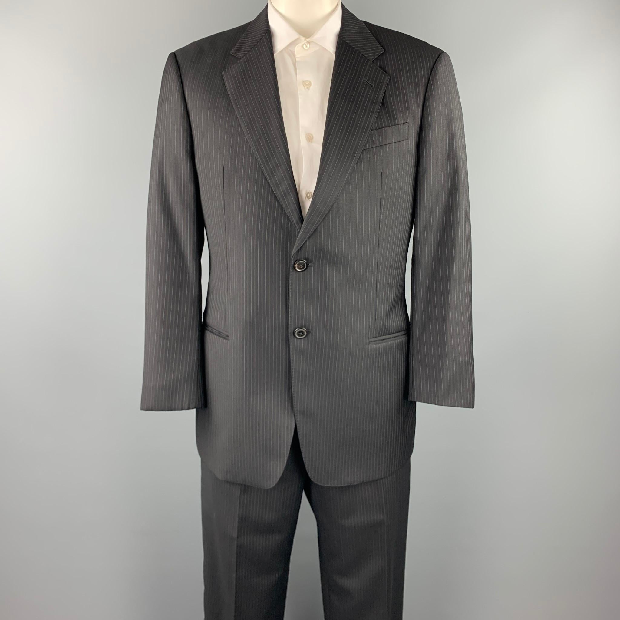 EMPORIO ARMANI suit comes in a black stripe wool with a full liner and includes a single breasted, two button sport coat with a notch lapel and matching flay front trousers. Made in Italy.

Very Good Pre-Owned Condition.
Marked: 42 R 
Original