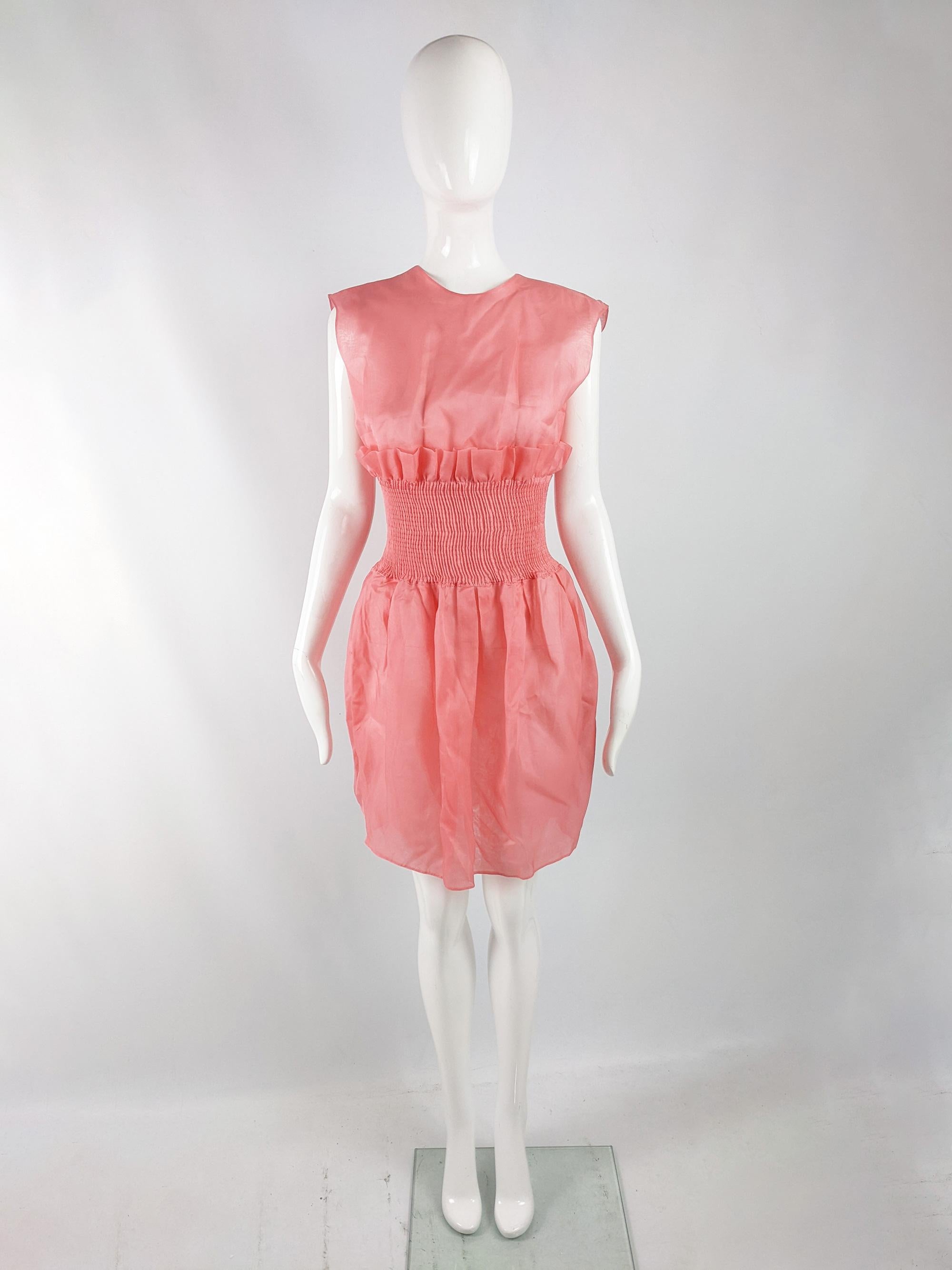 A stunning and rare vintage womens party dress by luxury Italian fashion designer Giorgio Armani for his Emporio Armani line, from the late 80s (probably the spring 89 collection). In a fully sheer, coral pink silk organza with a shirred waist that