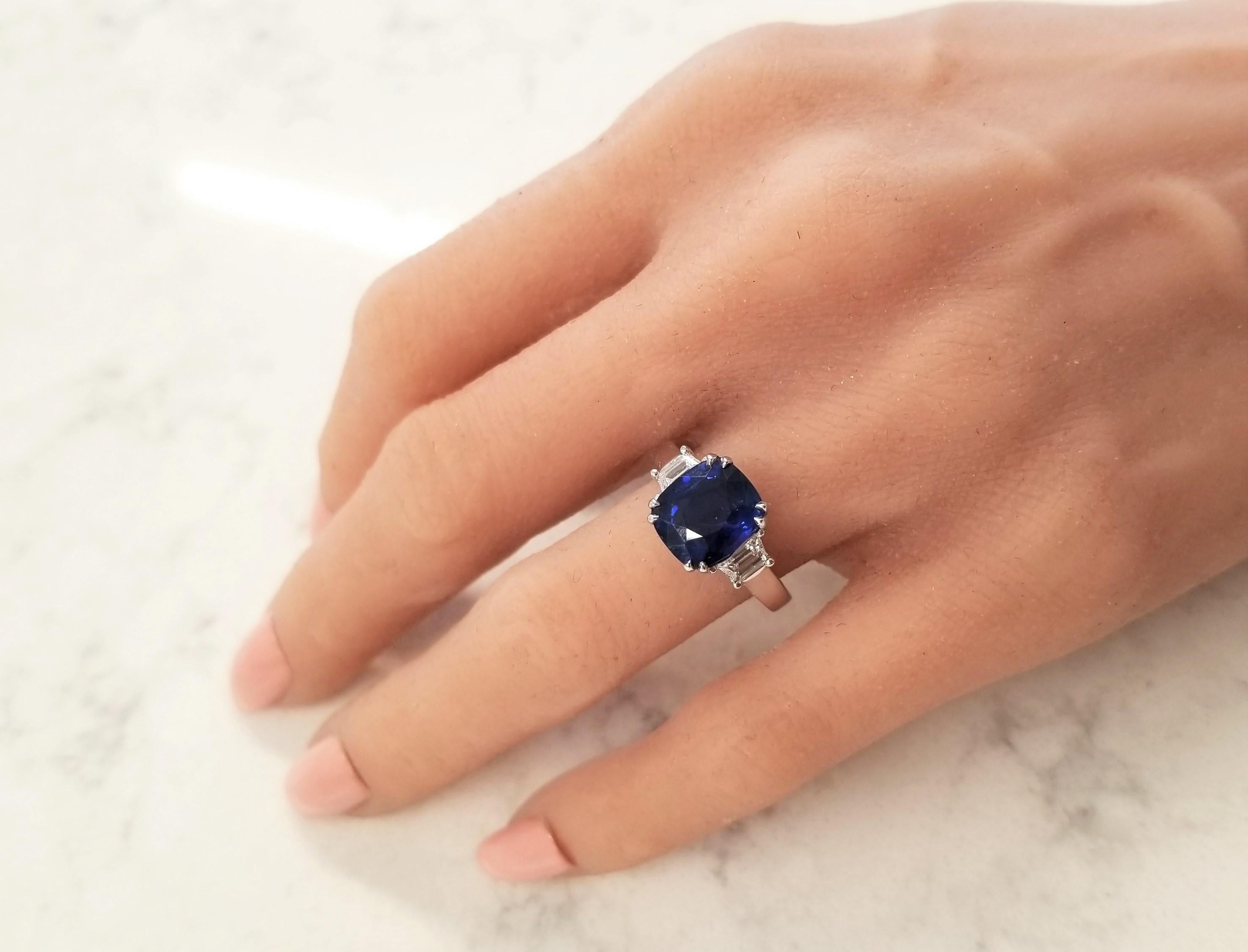 The spotlight is the 5.60 carat cushion cut blue sapphire. The gem source is Sri Lanka; its color is royal blue; its transparency and luster is superb. The color is alluring and is evenly distributed throughout the gem. Two step-cut trapezoid