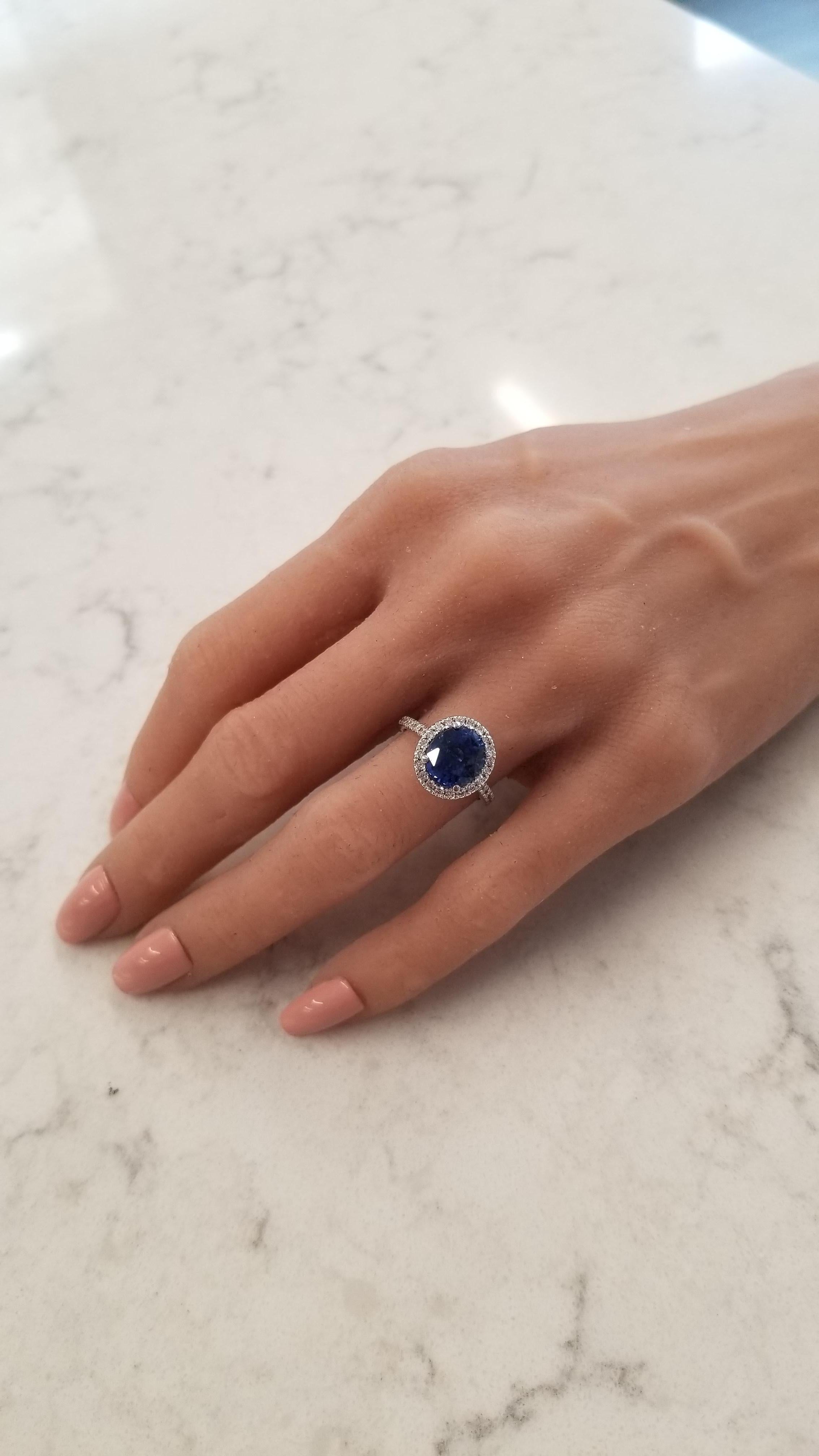This halo ring features a brilliant cut blue sapphire that takes center stage in a prong setting with a weight of 4.02 carats and measures 9.36x8.34mm. The gem source is Sri Lanka; its color is royal blue; its transparency and luster are excellent.