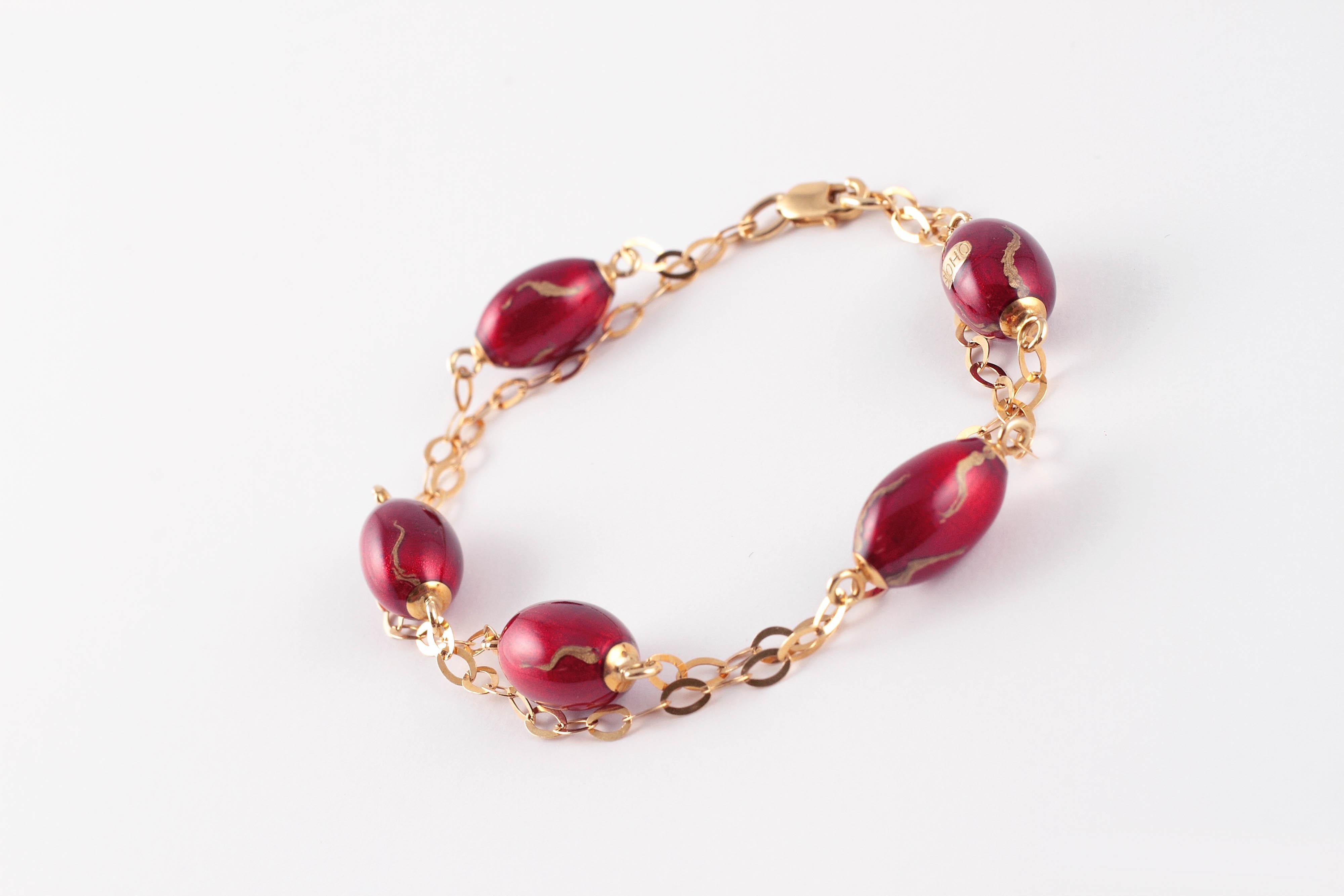 Wirklich ungewöhnlich!  Dieses interessante Armband besteht aus zwei Reihen ineinandergreifender flacher Glieder, die sich mit roten und emaillierten Perlen abwechseln und mit einem Karabinerverschluss aus 18 Karat Gelbgold gesichert sind. .