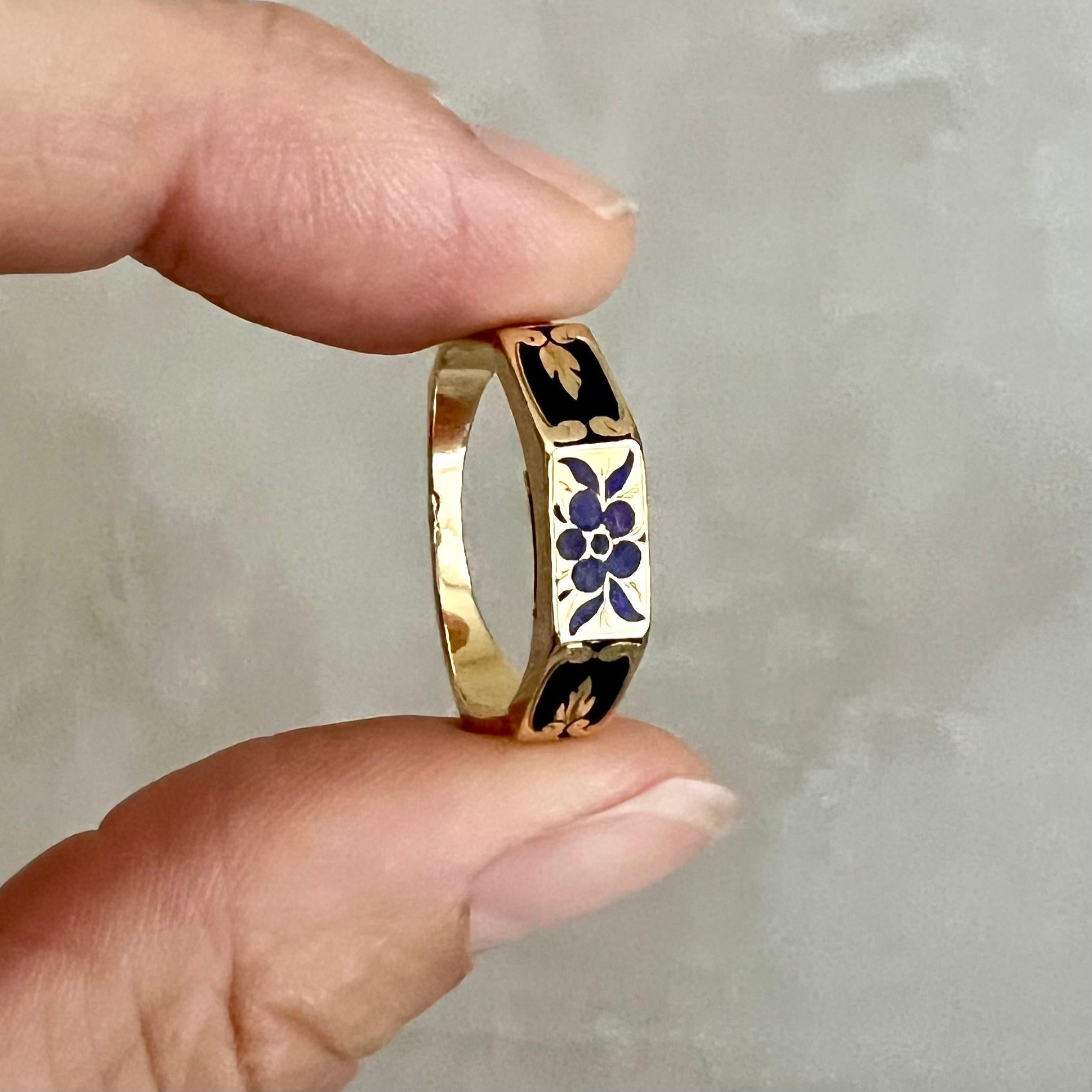 This antique Victorian memory ring is a finely crafted piece, designed in 18-karat gold and adorned with intricate black enamel. The enamel is decorated with a delicate floral design, featuring a 
