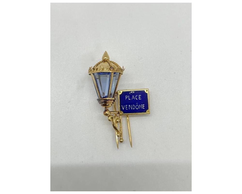Enamel and synthetic spinel brooch, 'Place Vendôme', Mauboussin, circa 1951 
Designed as a wall-mounted lantern set with calibré-cut sections of synthetic blue spinel, with a street sign reading 'Place Vendôme' in blue and white enamel, signed