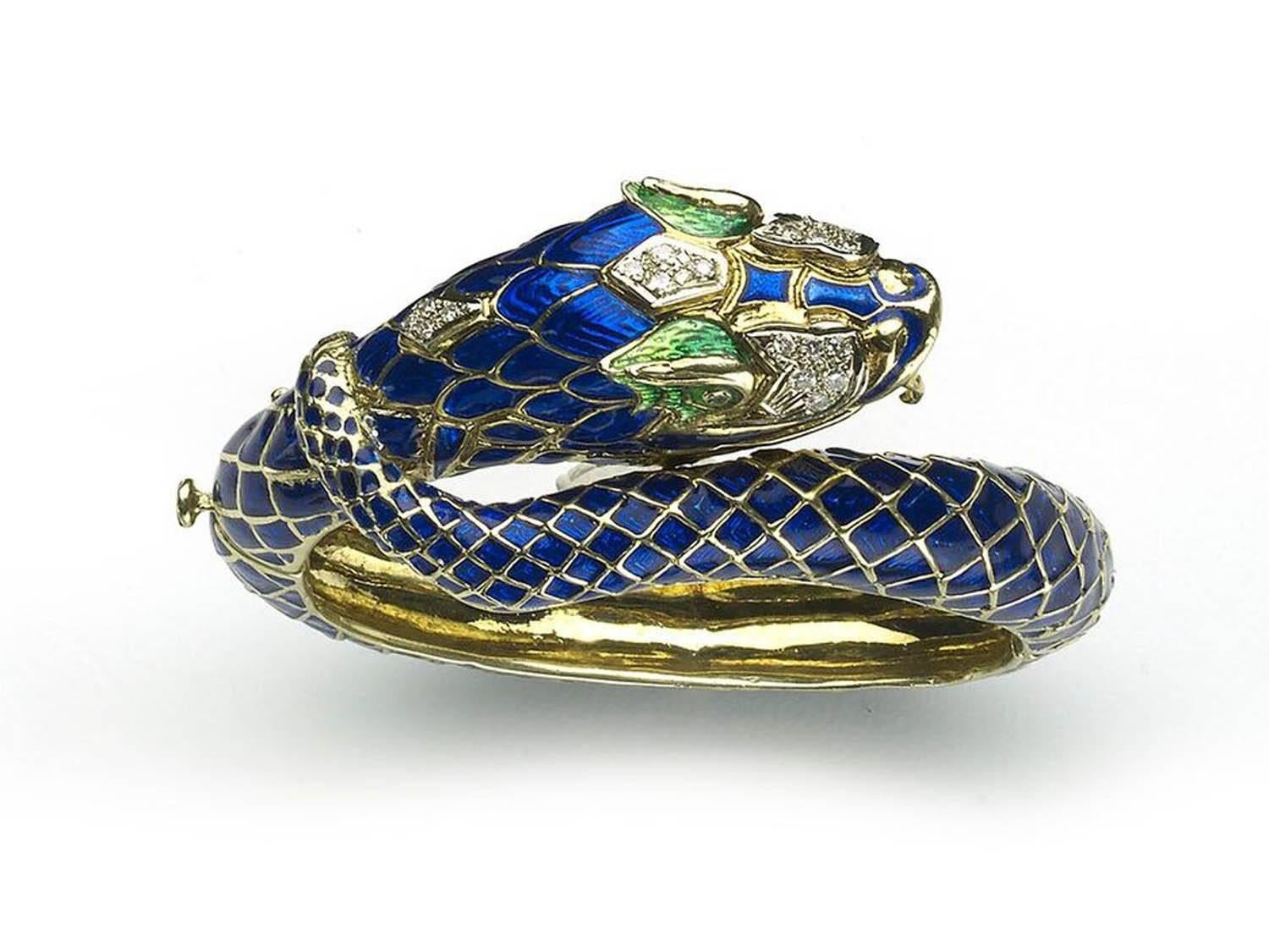 An enamel and diamond hinged snake bangle, with a blue enamel body, with green enamel detail around the eyes, and round brilliant cut diamonds set in the head, mounted in 18ct yellow gold. The inside diameter measures 43 x 55mm.