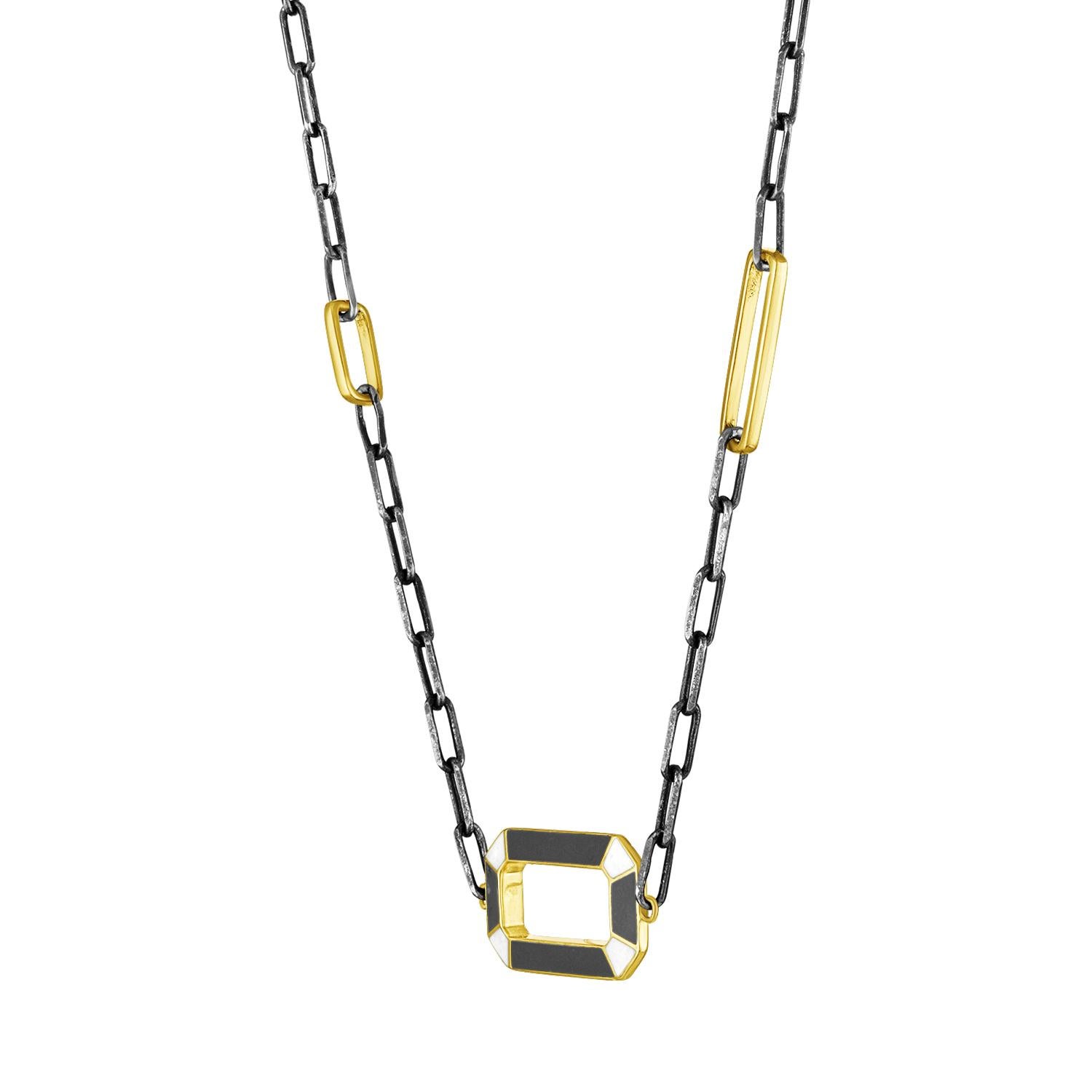 Une chaîne moderne et colorée qui présente un pendentif géométrique ouvert. L'émail a des couleurs différentes de chaque côté, pour s'adapter à votre humeur. Il est suspendu à une chaîne en argent oxydé en forme de trombone, avec deux maillons en or