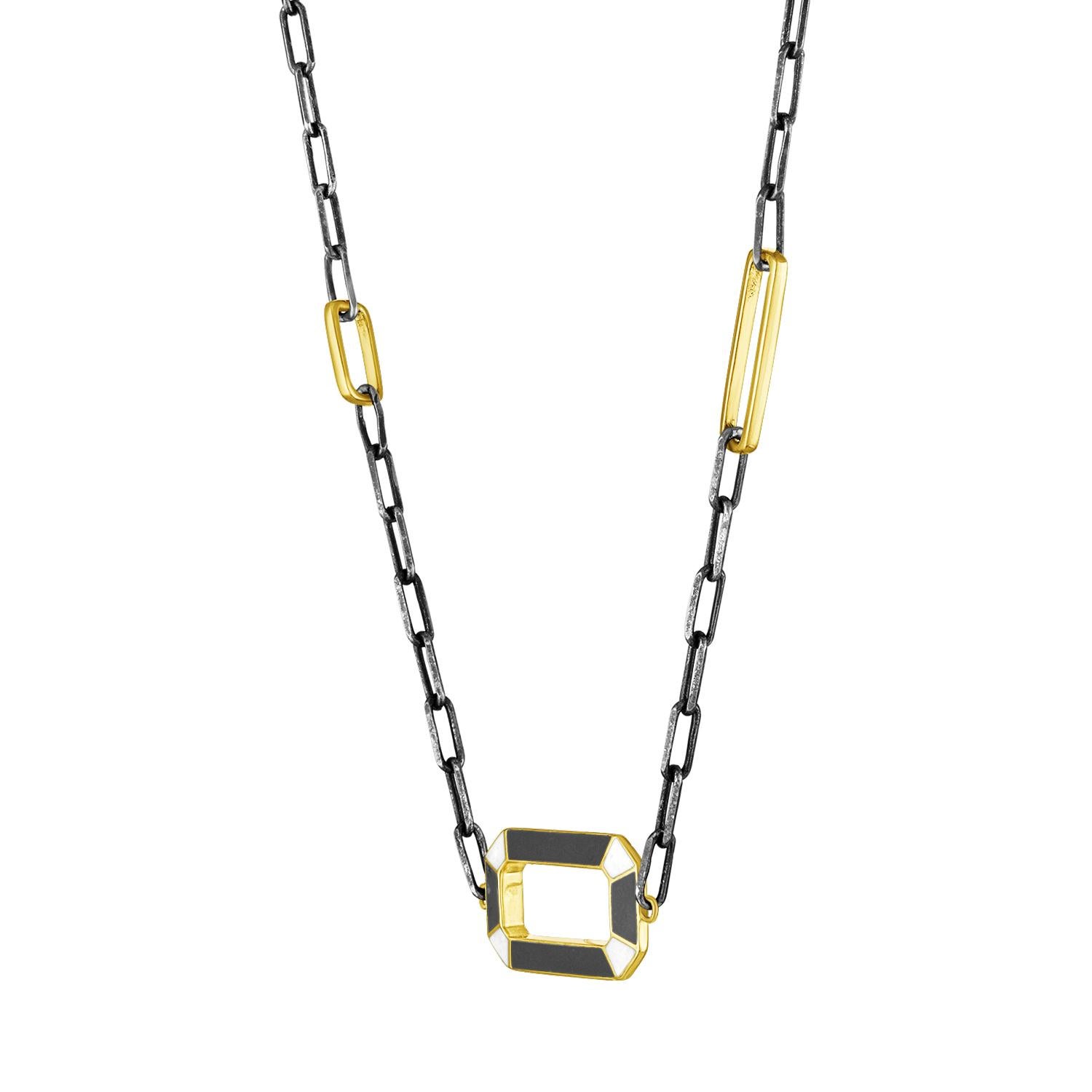 A modern and colorful chain that features a geometric open pendant. The enamel has different colors on each side, to suit your mood. It hangs from an oxidized silver paperclip chain, with two gold links that are larger and varied sizes. Classic, yet