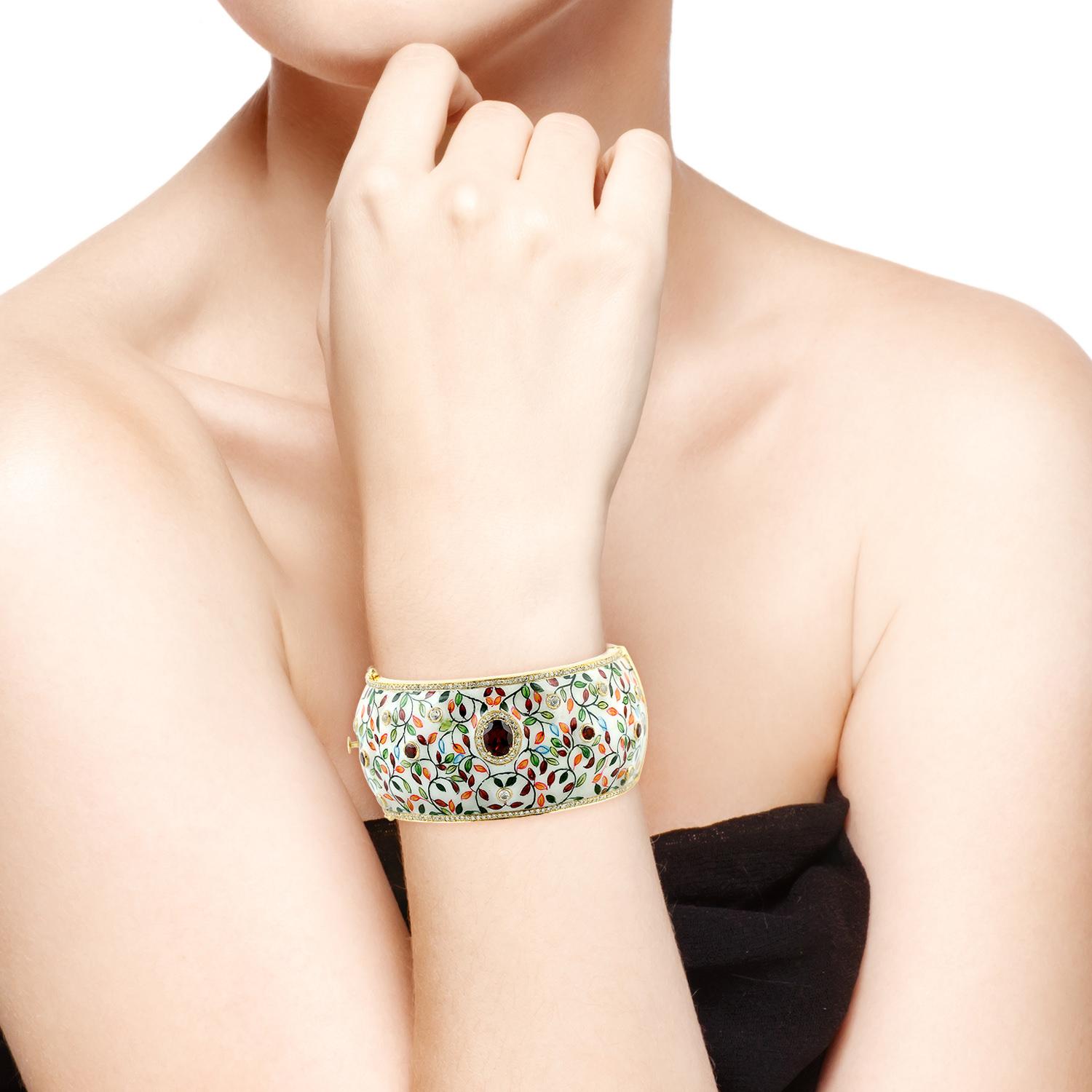 Le bracelet en émail présente un art miniature unique peint à la main. Il est fabriqué en or 18 carats et en argent sterling. Elle est sertie à la main de 6,6 carats de grenat, 2,5 carats de topaze et 2,33 carats de diamants.  Fermeture par