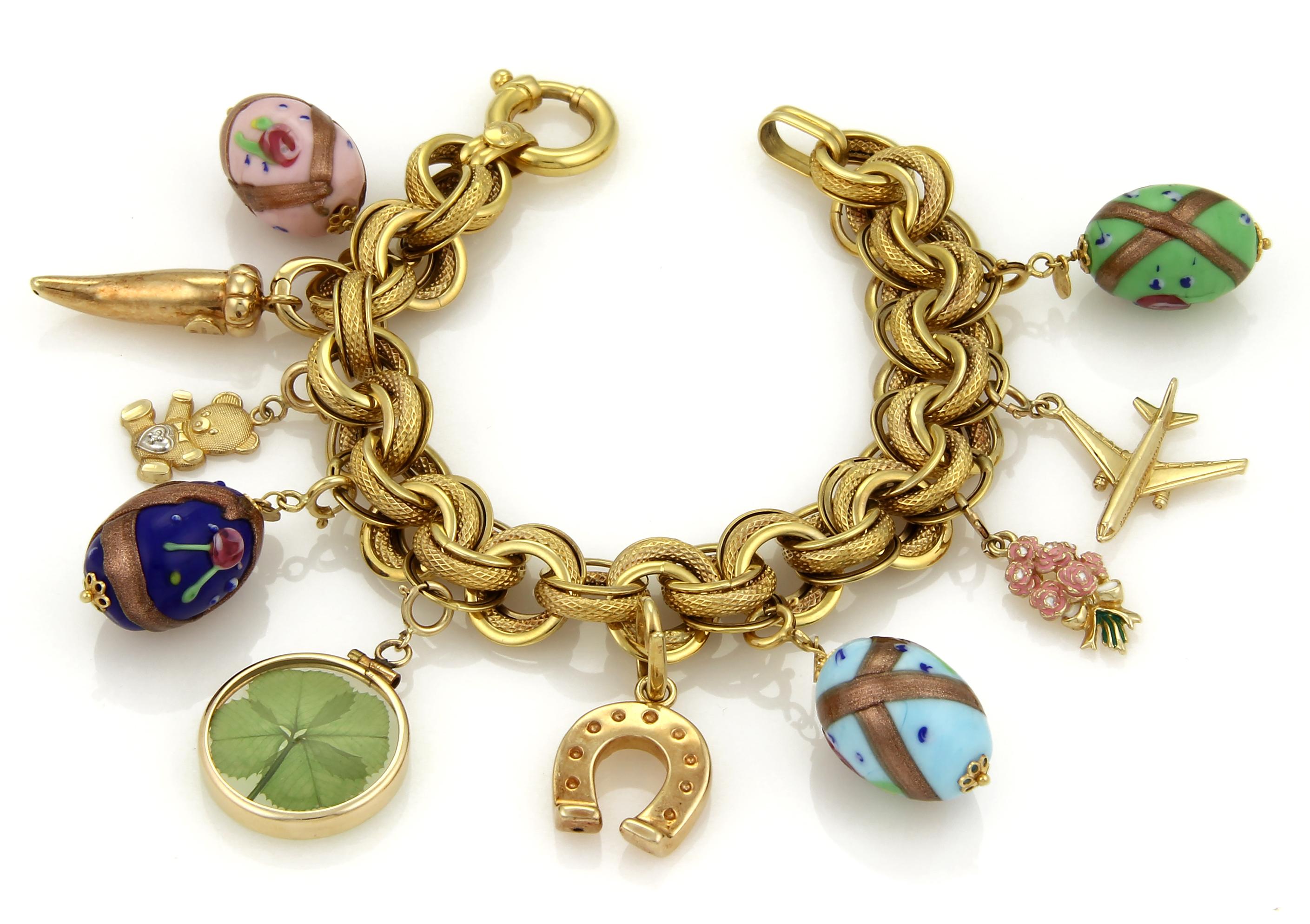 This is a gorgeous large hefty charm bracelet, it is crafted from solid 14k yellow gold and has large textured and polished triple round charm links, there are 10 large charms dangling from the bracelet, they are four oval eggs, each with fancy