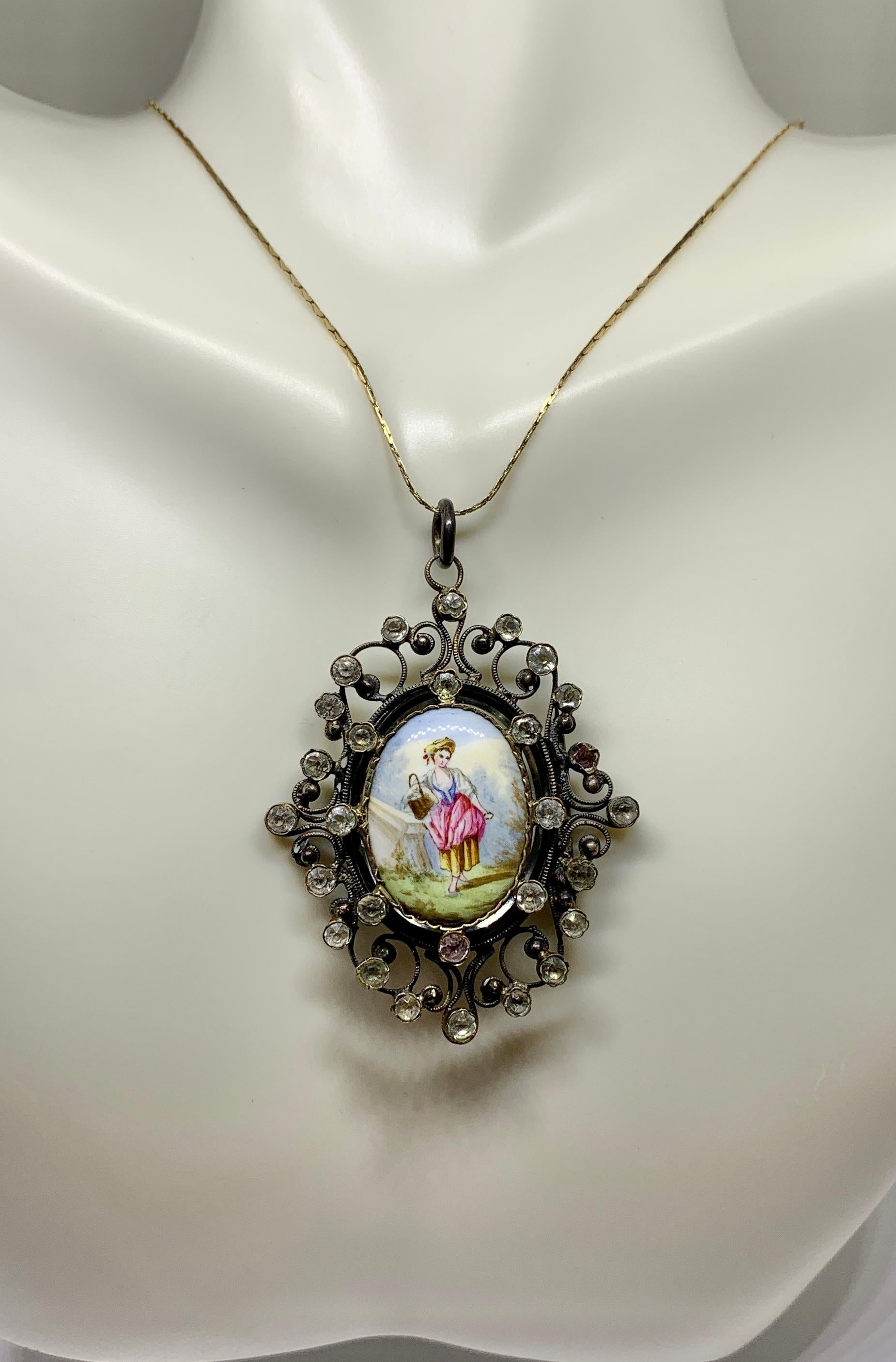 This is a gorgeous Locket Pendant with a hand painted enamel scene of a woman with her basket of eggs in a pastoral scene surrounded by a wonderful filigree silver setting with paste stones.  The early antique jewel dates to the 19th Century.  The