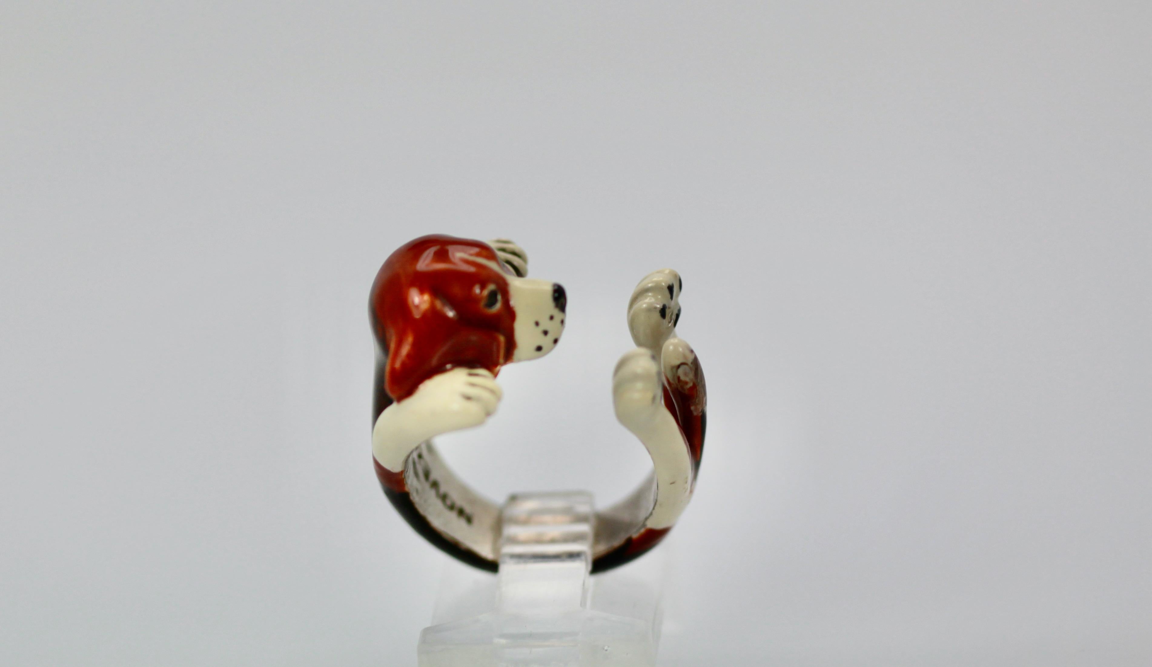 This humorous dog ring is done in ceramic and on silver depicting a dog on his back showing his belly. This dog is a beagle detailed with extreme accuracy as his body wraps around the finger with his head legs and paws and tail showing.  When I