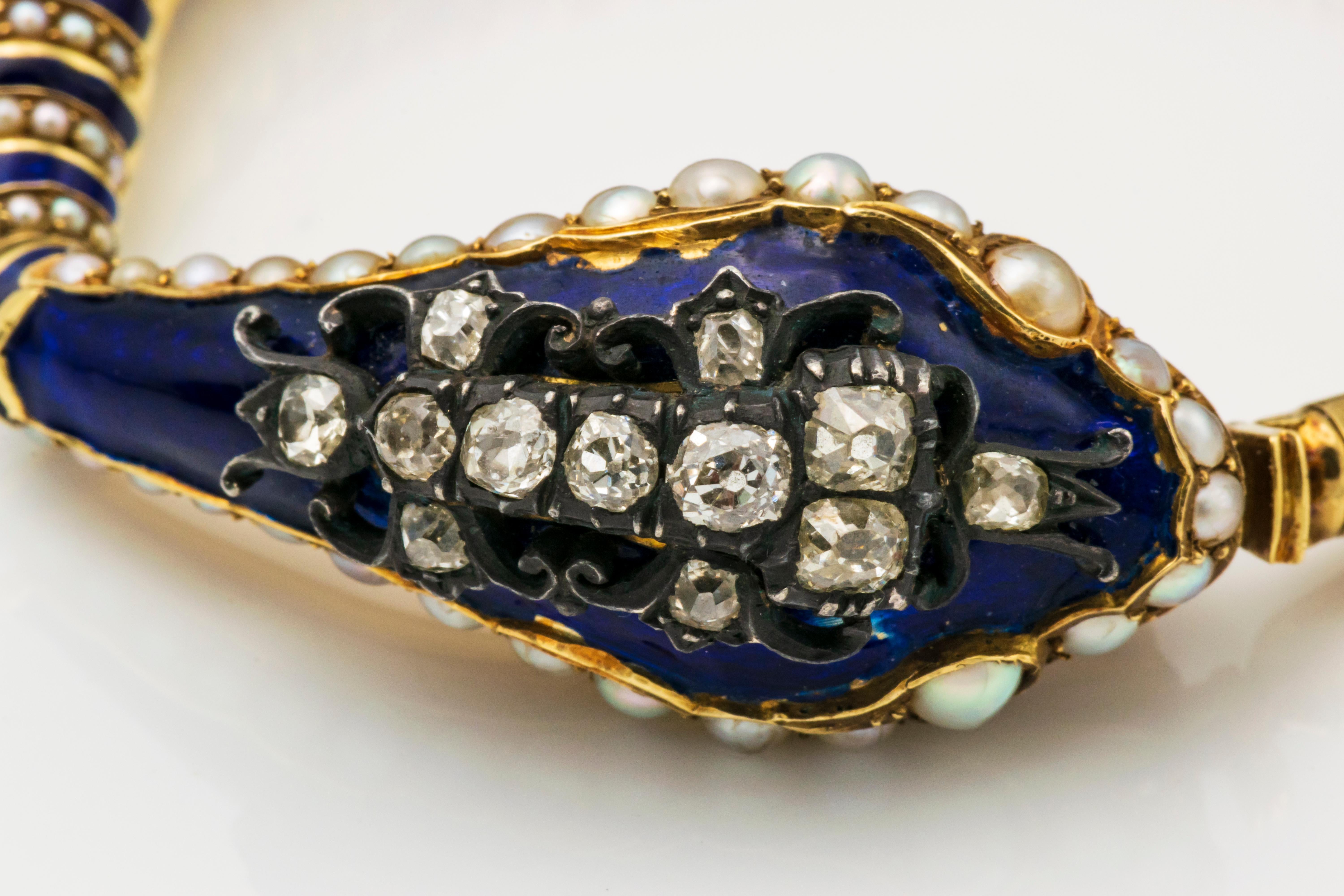 Designed as serpent, the gold head inset with split pearls, applied with blue enamel, surmounted with an openworks silver motif set with twelve old mine-cut diamonds, the body composed of nesting hemispherical links applied with alternating blue