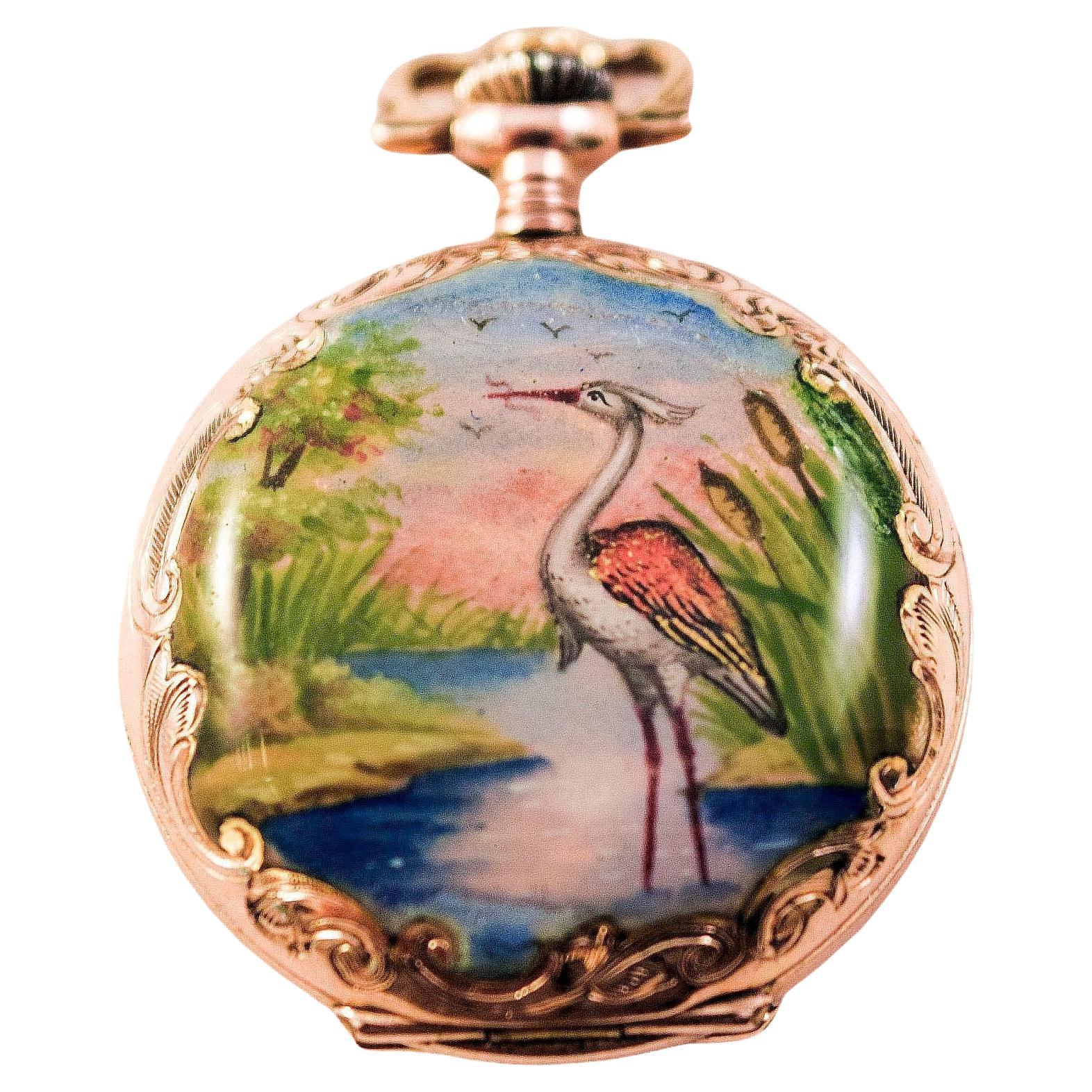 Enamel Pocket Watch Hunter case with lovely tropical landscapes and Heron enamel painting on the other side
Case is solid 14ct yellow gold,
 White circular dial with black painted numerals,
 one side with an enamelled scene of a tropical landscape,
