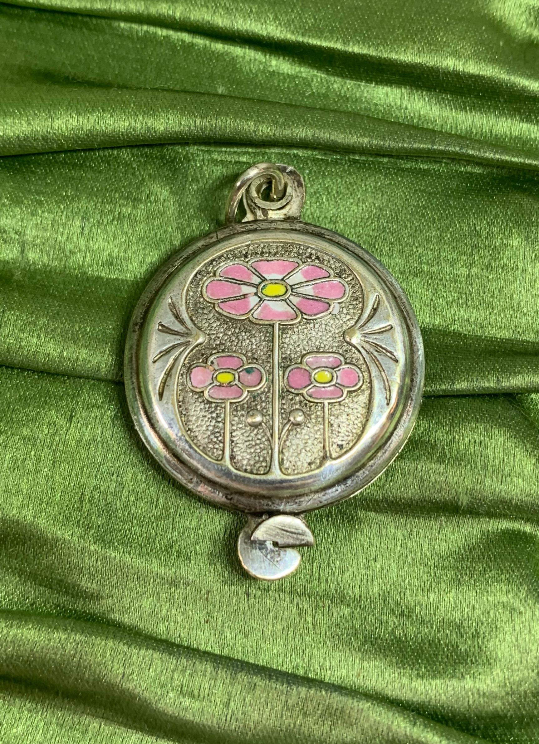 IL S'AGIT D'UN MAGNIFIQUE ET RARE COLLIER MÉDAILLON ART NOUVEAU JUGENDSTIL AVEC UN SUPERBE MOTIF DE FLEUR DE PAVOT ROSE EN ÉMAIL SUR LES DEUX CÔTÉS DU MÉDAILLON EN ARGENT AVEC UN BEAU MOTIF EN RELIEF D'UNE FLEUR DE PAVOT ET D'UN MOTIF DE FEUILLE.
Ce
