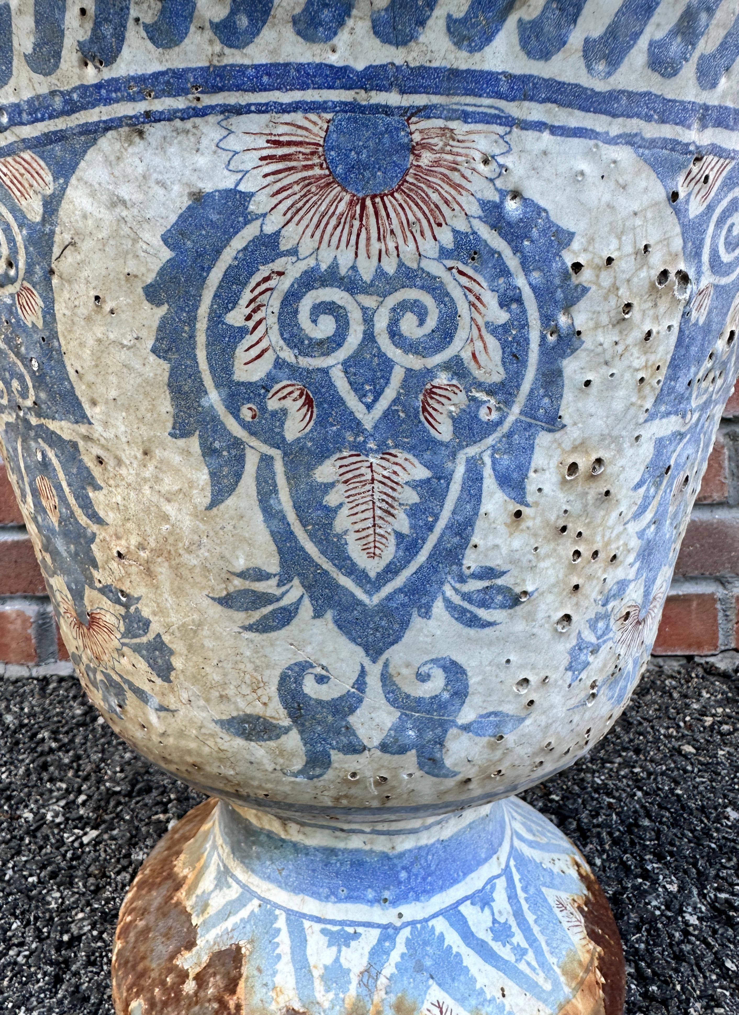 Enameled cast iron Rouen urn decorated in blue and red on white colors. This late 19th century enameled urn is relatively large in size and function both outdoors as a planter or indoors as a vase or cache-pot with the addition of a liner.